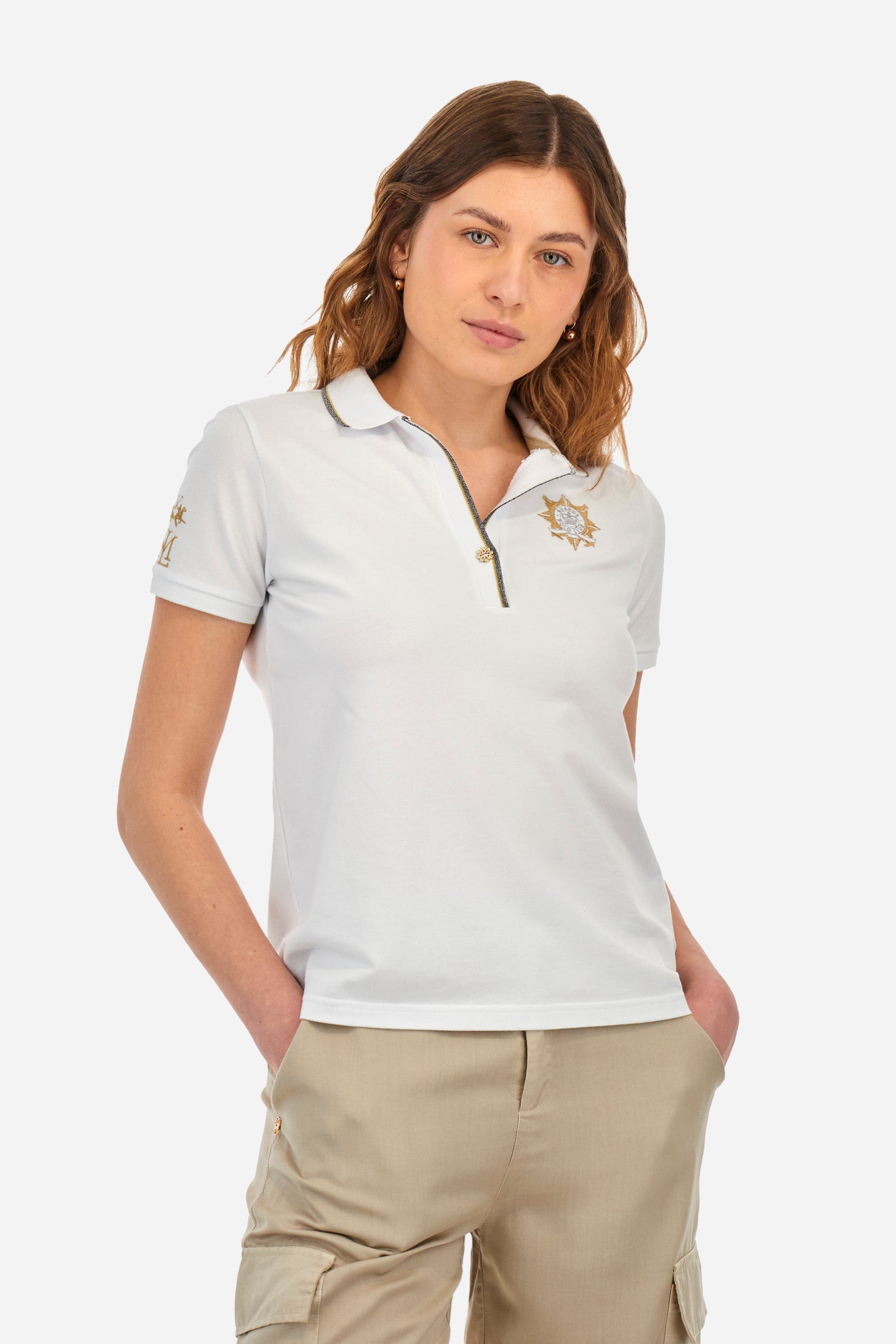 Women’s polo with short sleeves in solid color. Made of stretch cotton. V-neck and jewel button closure. Ribbed crew neck and armhole, both profiled by a lamé strip. The under collar embellished with a different color print along with mini logo and symbol on the chest and sleeve are characteristic of the capsule Guards. The fit is regular. The model wears a size 2. - Optic White