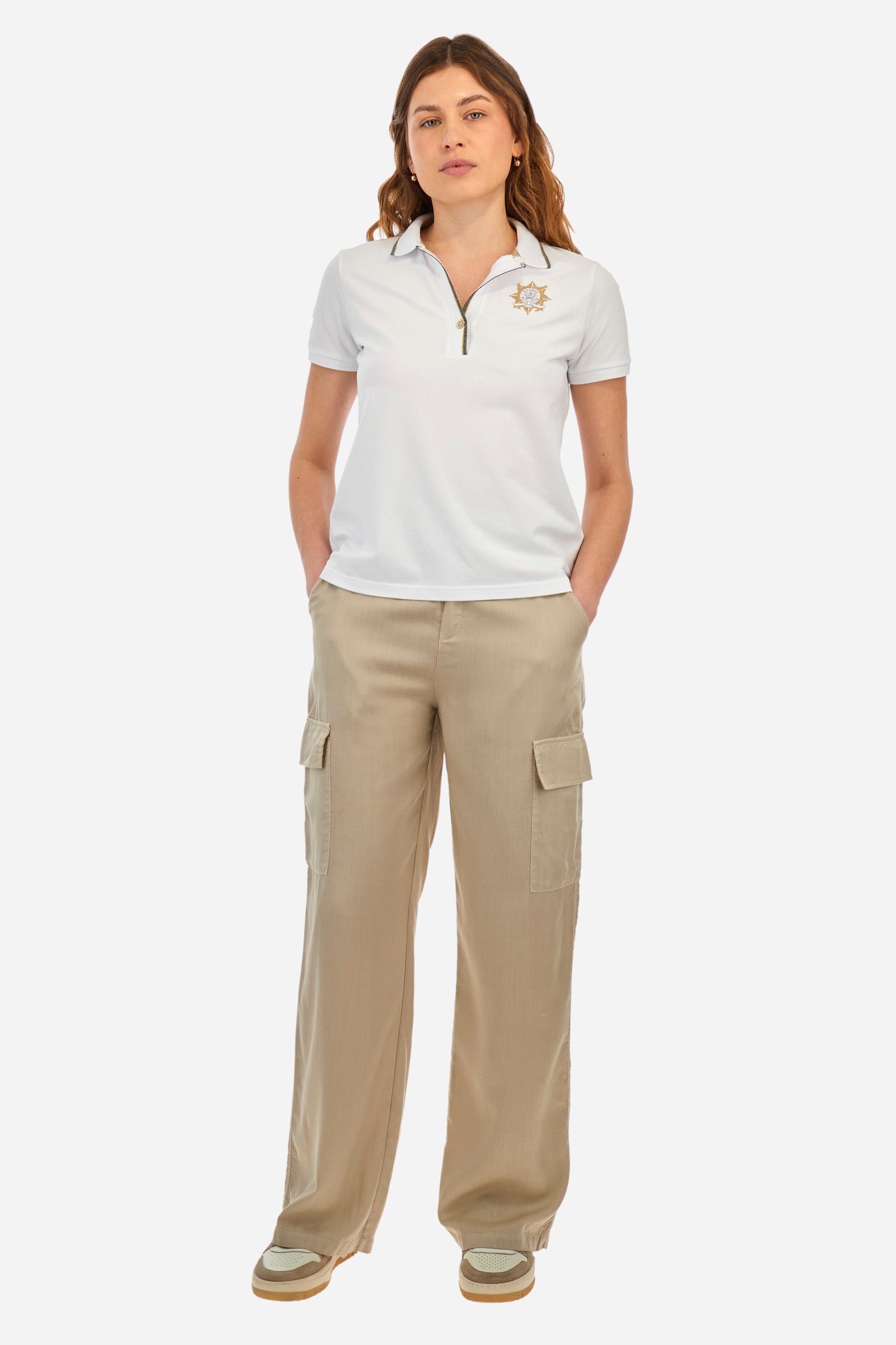 Women’s polo with short sleeves in solid color. Made of stretch cotton. V-neck and jewel button closure. Ribbed crew neck and armhole, both profiled by a lamé strip. The under collar embellished with a different color print along with mini logo and symbol on the chest and sleeve are characteristic of the capsule Guards. The fit is regular. The model wears a size 2. - Optic White