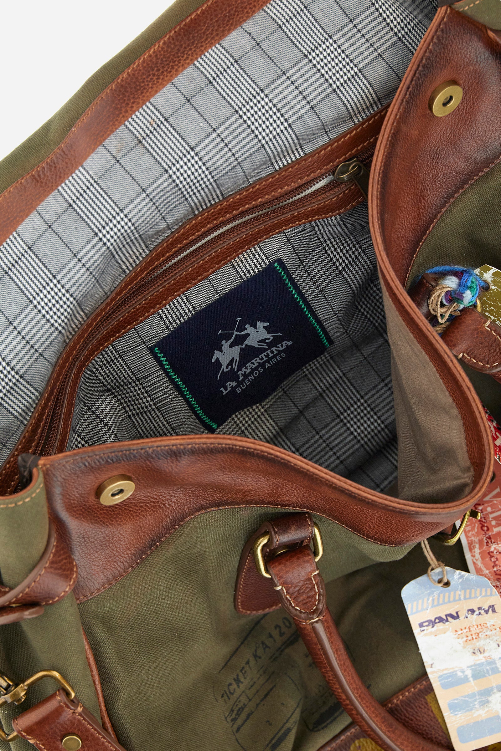 Unisex bicolor duffel bag made of 100% leather. Snap button closure. Equipped with two handles and a removable shoulder strap. Inside, there is a zippered pocket. Iconic design of the brand, embellished with writings, patches, and applied labels throughout the accessory. The La Martina logo is on the back. Dimensions (width x height x depth) 68x43x26 cm. - Military Olive