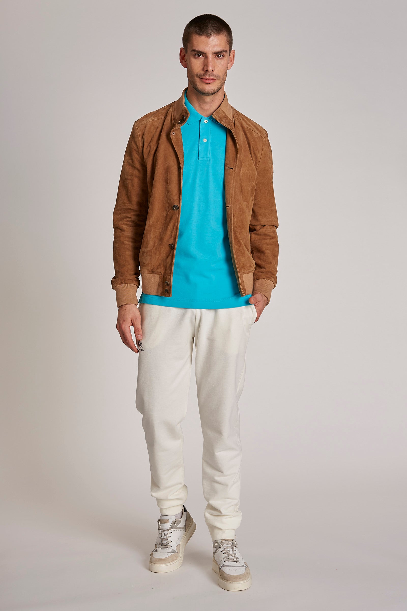 Men's regular-fit suede bomber jacket. Crew neckline and front button fastenings. Fabric hem, sleeves and collar for maximum comfort. La Martina logo appliqué on the sleeve. Part of the Blue Ribbon Capsule Collection, it is ideal for adding a touch of originality to a sporty or casual look. The regular fit adapts perfectly to any body type. The model is 187 cm tall and wearing a size L. - Dijon