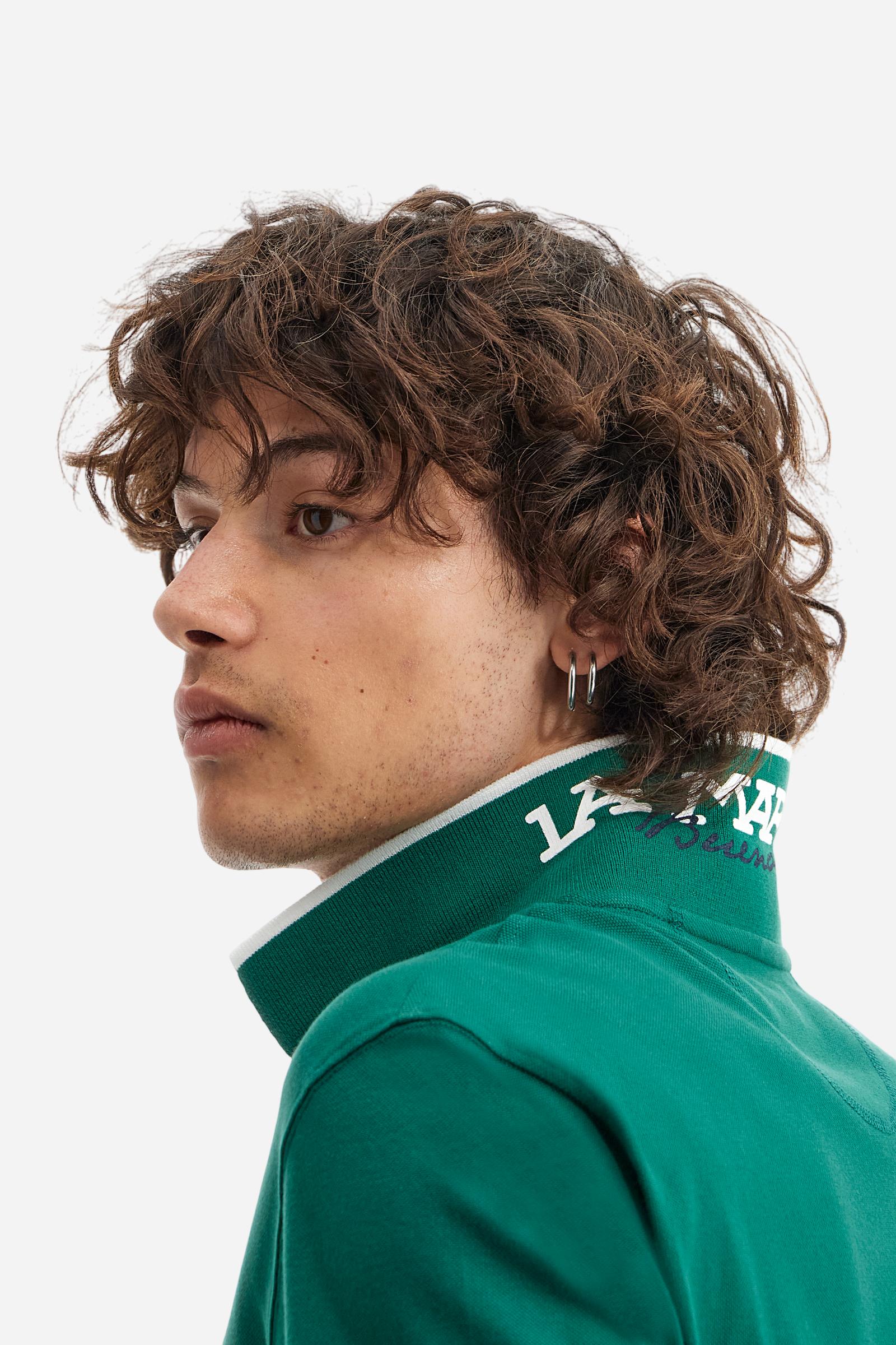 Short-sleeved, single-colour men's polo shirt made of stretch cotton piqué. Fastens with two buttons. The collar and cuffs are ribbed, and there is a colour-contrasting trim at the bottom of the collar. Inside the collar there is a grosgrain ribbon of a different shade. The logo is embroidered on the chest in a contrasting colour. The fit is slim. The model is wearing a size L. - Evergreen