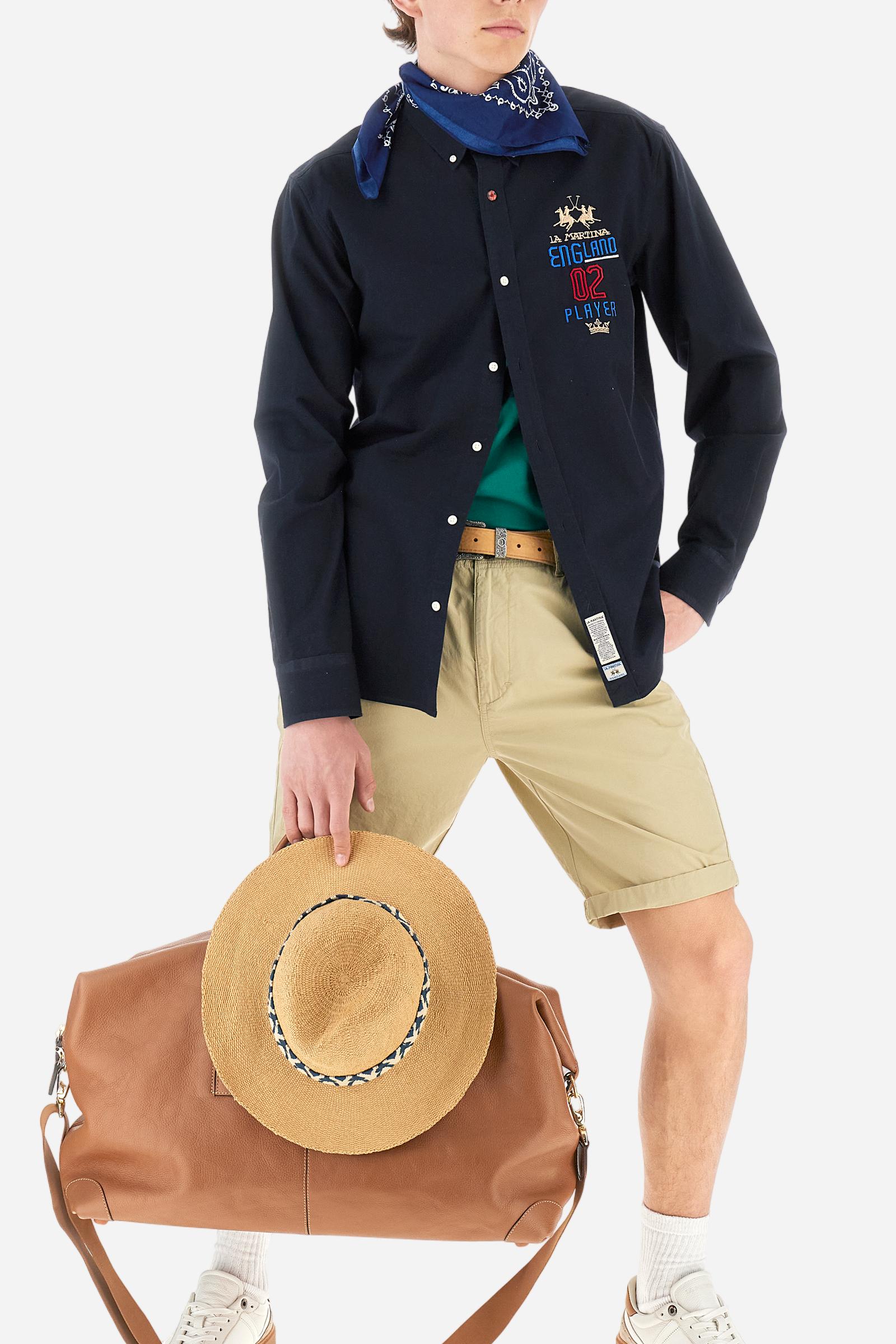 Men's long-sleeved plain shirt made from 100% Oxford cotton. The button-down collar is finished with a second button printed with the English flag. The multicoloured embroidery on the chest, over the heart, includes lettering, numbers and the logo, which add a distinctive touch. Regular fit. The model is wearing a size L. - Navy