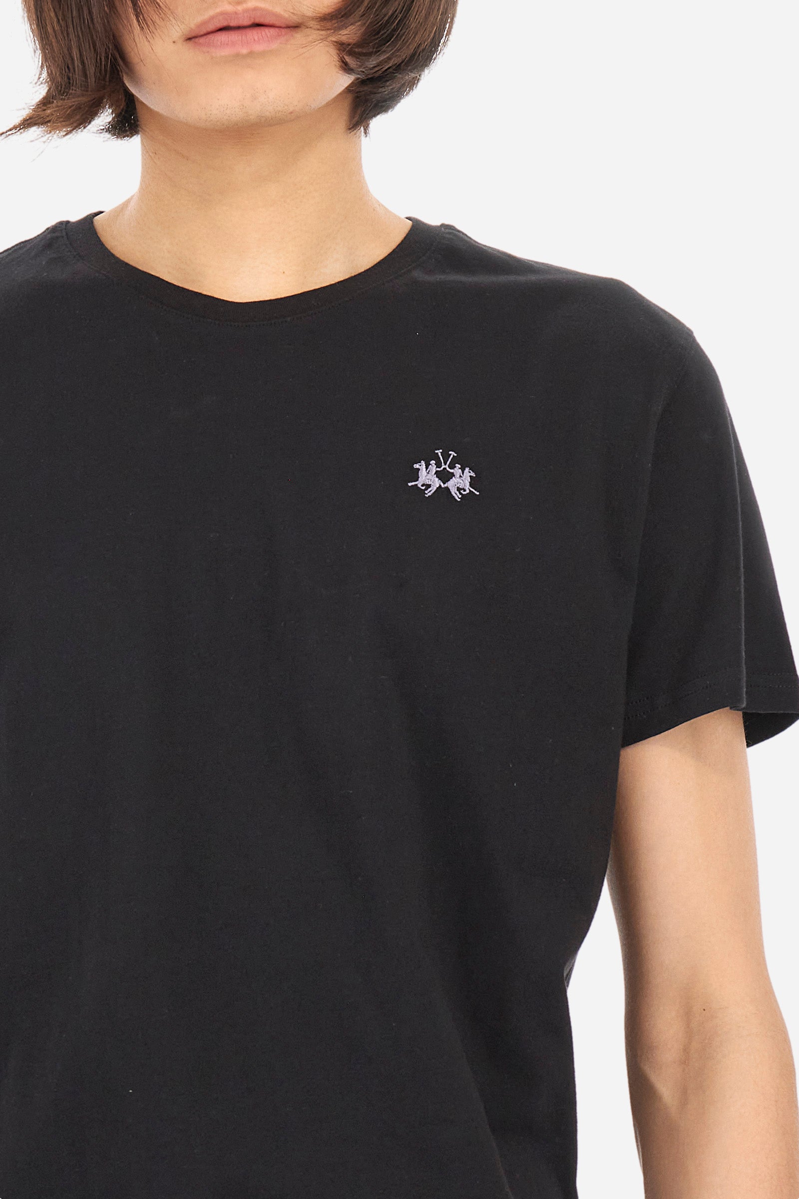 Men's short-sleeved crew-neck T-shirt in solid colour with embroidered logo in contrasting colour on the chest. Made of 100% cotton with a regular fit. It is perfect paired with Bermuda shorts or trousers for a casual and trendy look. Suitable for leisure time. The model is 187 cm tall and wears a size L. - Black