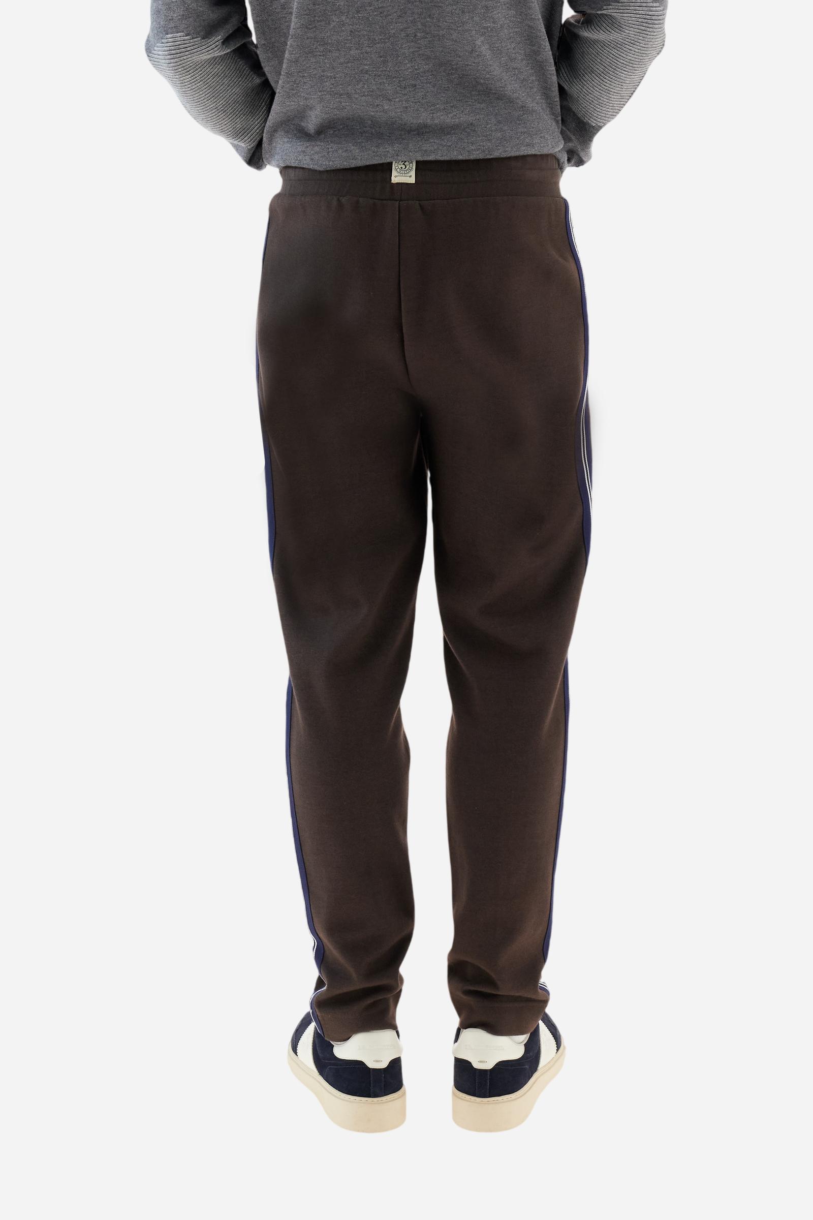 Men’s joggers made of 100% cotton interlock fleece with a bicolor design. Elastic waistband with drawstring for a customizable fit. Two zipped side pockets add practicality, while multicolor striped tape decorates both sides. A vertical crease on the front leg adds refinement to this sporty style. Small embroidered logo in contrast under the left pocket. Regular straight-leg fit for a classic, comfortable silhouette. Model wears size L. - Java