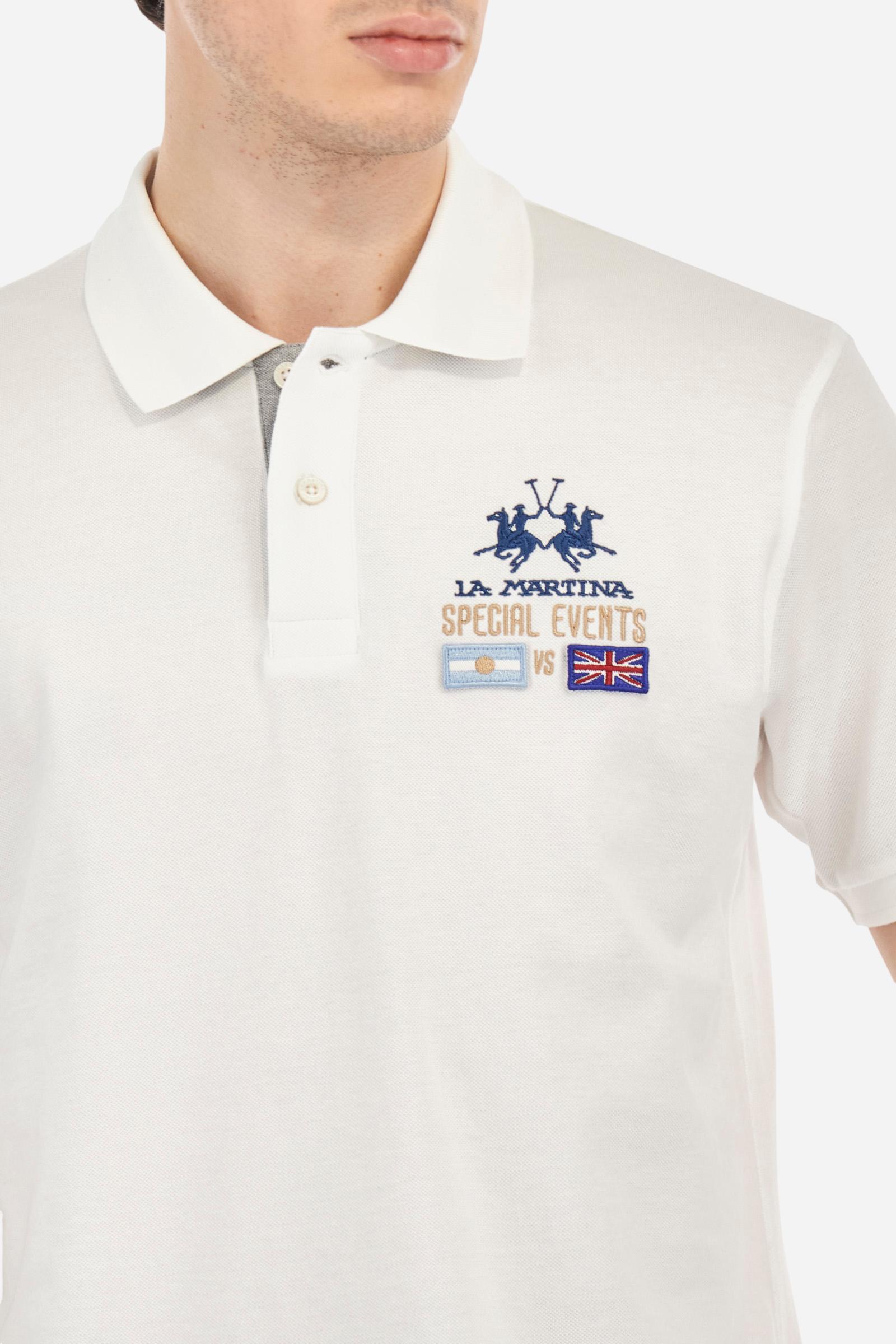 Men's plain short-sleeved polo shirt made from cotton piqué. Two-button fastening. The collar and cuffs are made from tone-on-tone ribbed fabric. The inside of the placket is also made from piqué, but in a contrasting colour. On the left side of the chest, in addition to the embroidered logo in contrasting thread, there are small patches of the Argentine and English flags. Regular fit. The model is wearing a size L. - Optic White