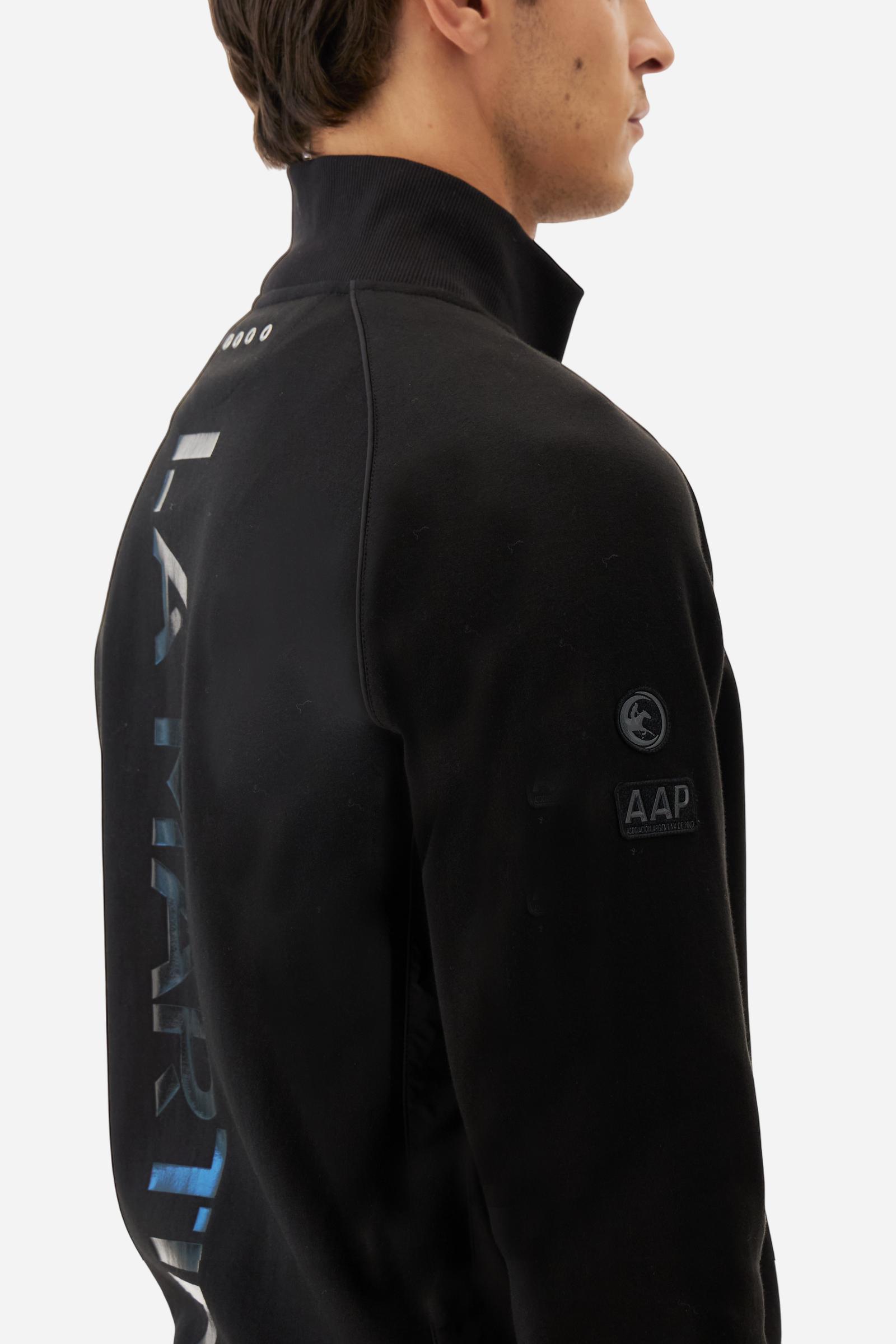 Men's long-sleeved sweatshirt in solid cotton-blend interlock with semi-glossy finish. Features customised front zip, stand-up collar, hem and cuffs in tone-on-tone rib. Large semi-gloss La Martina transfer on the back celebrates the brand's identity, while two patches on the right sleeve recall the Argentine polo association. Regular fit for a practical yet refined style. Model wears size L. - Black