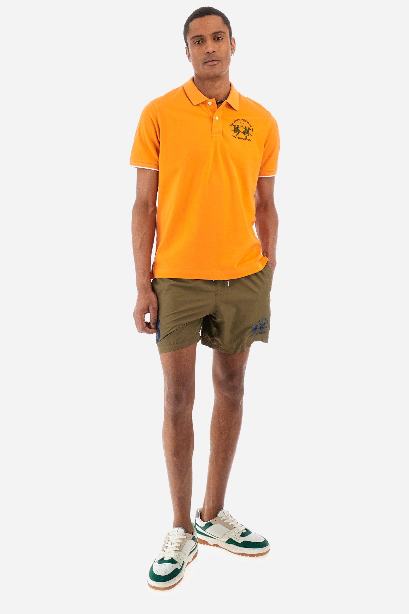 Men’s polo with short sleeves, regular fit. Made of stretch pique cotton. Classic model, with large embroidered logo in contrasting tone on the chest and profiled sleeve edges. The collar is accompanied by the writing La Martina, in contrasting tone. Ideal if worn with a denim collection. The model wears a size L. - Celosia Orange