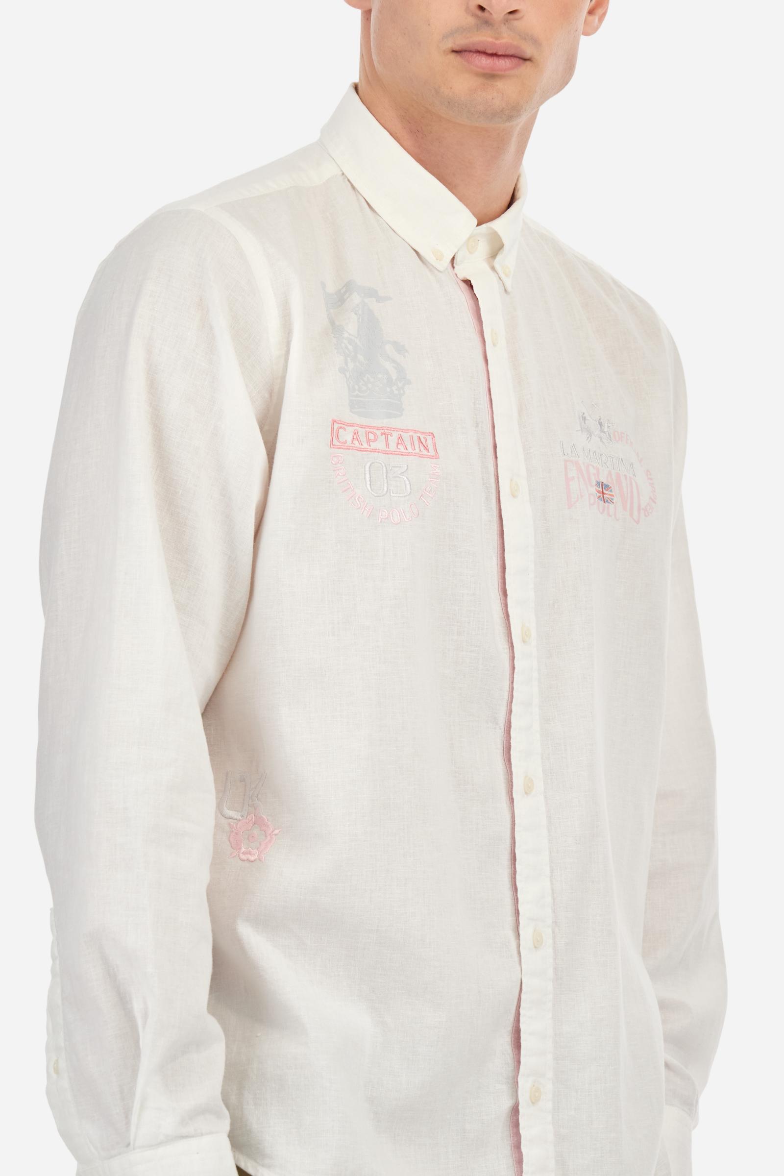 Men's long-sleeved single-colour shirt made of cotton and linen canvas. Button-down collar. Featuring details on the inside of the collar and opening in contrasting colour printed fabrics. The front graphics and logo are embroidered with contrasting colour threads. The fit is regular. The model is wearing a size L. - Optic White