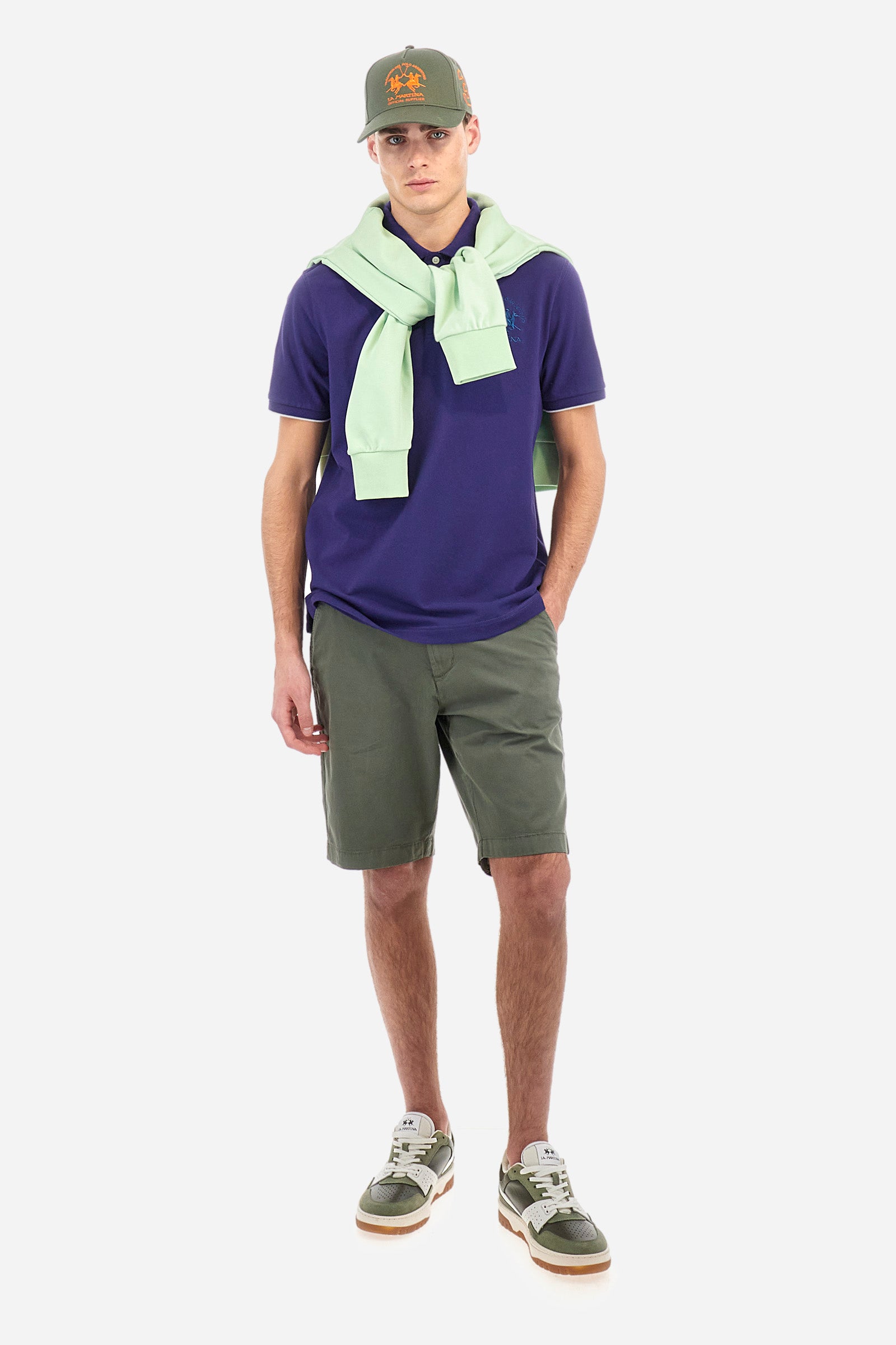 Men's plain short-sleeved polo shirt made from stretch piqué. Featuring a two-button fastening and a ribbon on the inside collar in contrasting coloured grosgrain. The collar and cuffs are in matching rib knit, with the undercollar also in rib knit but in a contrasting colour. The large logo is embroidered on the chest, left side with contrasting coloured thread. The undercollar features a print of the La Martina lettering in a contrasting colour. Regular fit. The model is wearing a size L. - Deep Cobalt