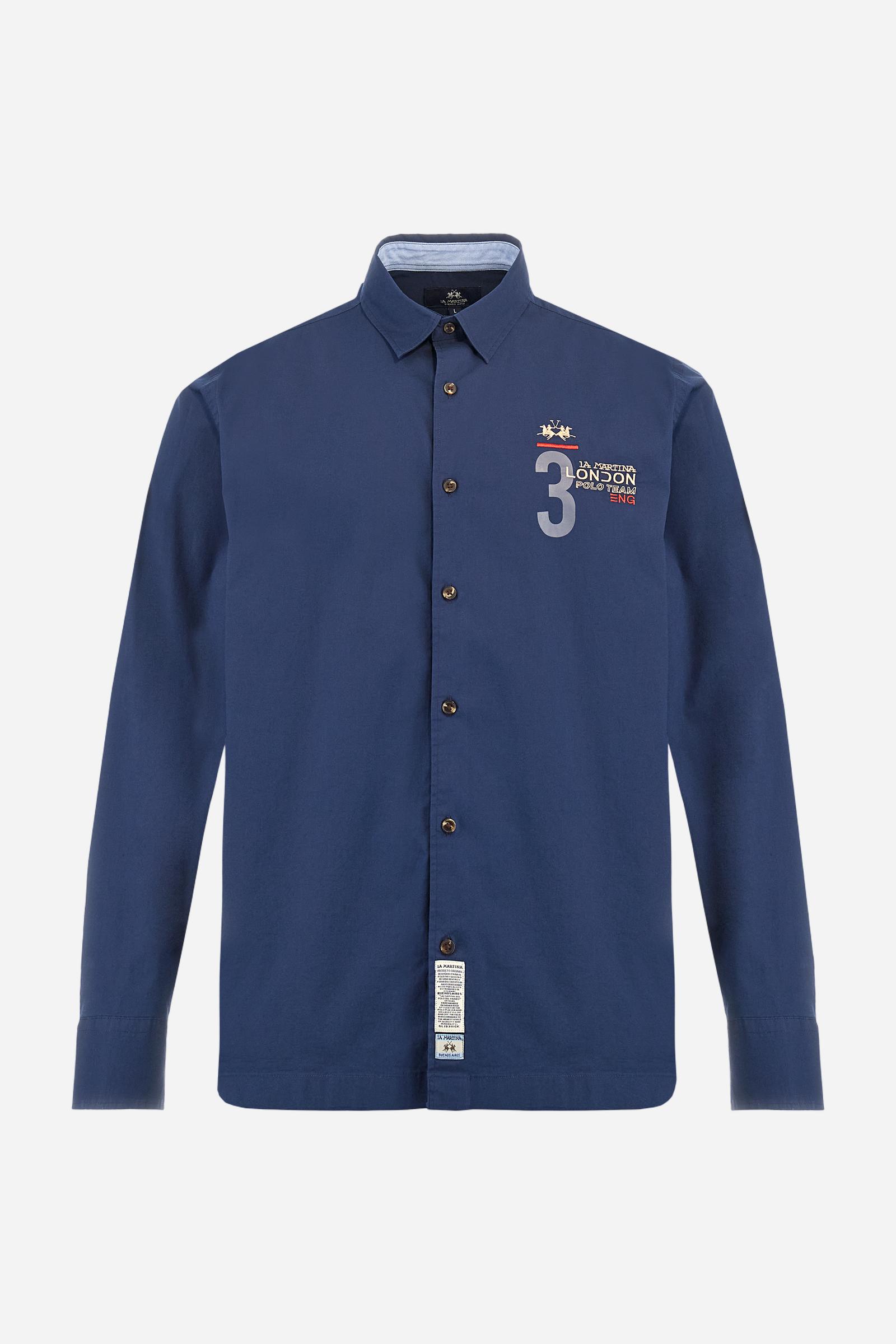 Men's single-colour long-sleeved shirt, made from 100% cotton poplin. Spread collar. Contrasting printed fabric details on the inside of the collar and opening. The numbers on the chest and back graphics are rubberised prints, while the rest of the graphics are embroidered. The logo and La Martina lettering is embroidered on the left chest. The fit is regular. The model is wearing a size L. - Navy