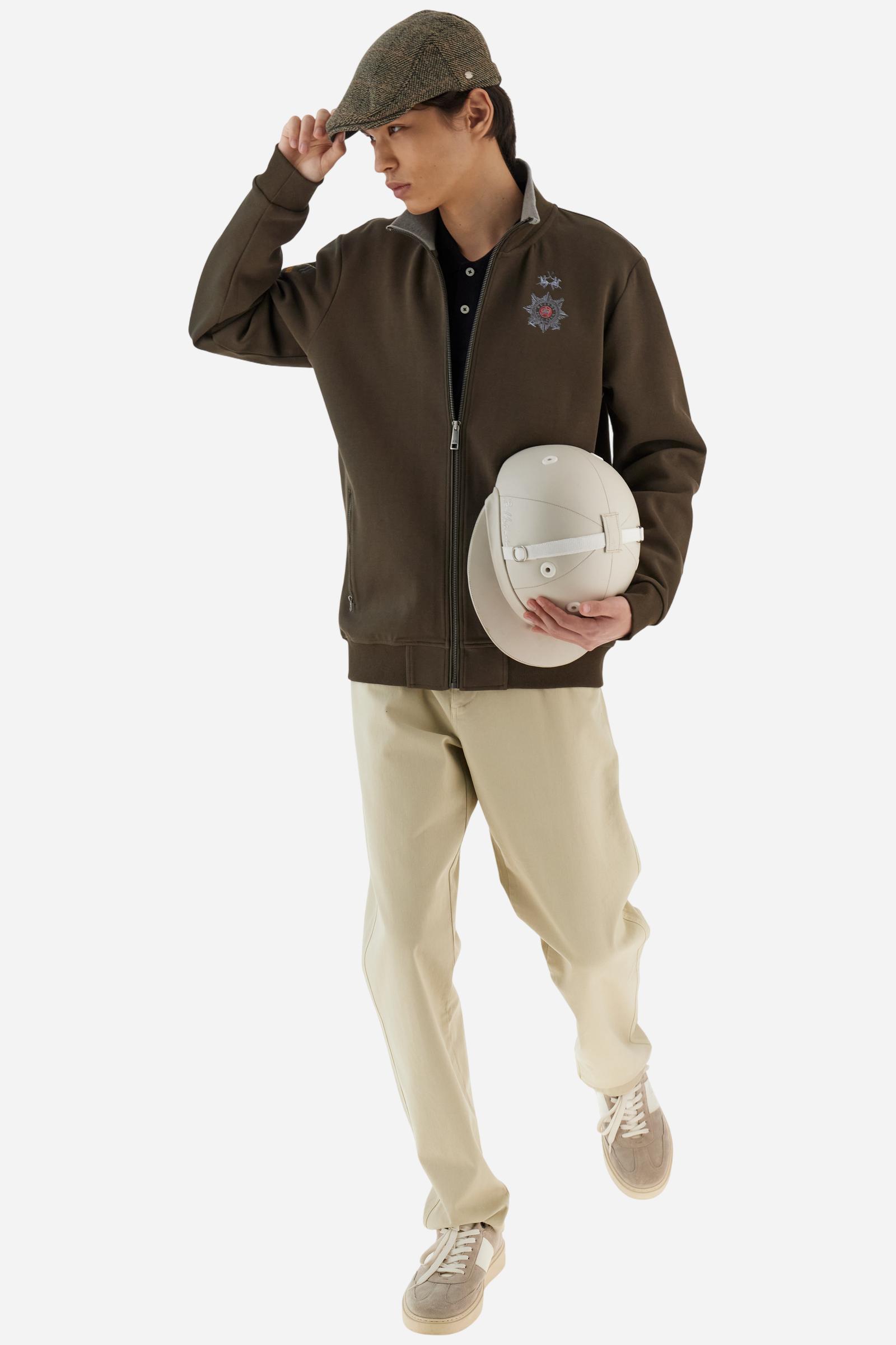 Men's long-sleeved, full-zip solid colour sweatshirt. Made of stretch cotton-blend piqué. Design with front opening fastened by a zip, high collar in two-tone ribbing. Solid colour ribbed cuffs and waistband. The small brand logo and Guards crest are embroidered in multi-coloured thread on the chest. On the right sleeve, there is another embroidery of a crest inspired by the British royal household. The regular fit silhouette is practical for everyday wear. The model is wearing a size L. - Java