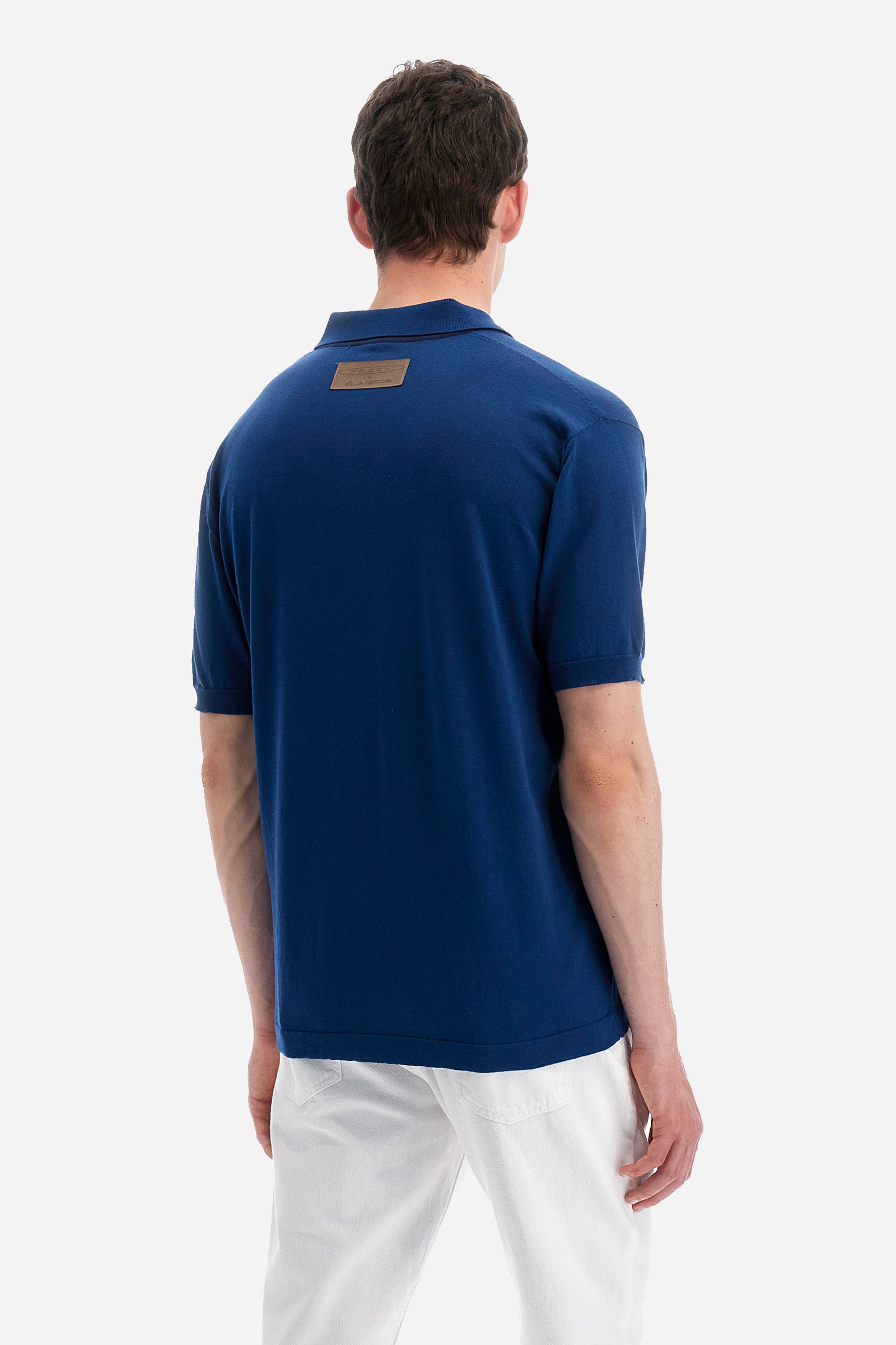 Single-colour men's knitted polo shirt with short sleeves from the line in collaboration with Pagani. Made of 100% cotton. Fastens with a button. Ribbed armholes and waist. The logo and "La Martina" and "Pagani" lettering are present on the patch representing the collaboration applied on the back. The fit is regular. The model wears a size L. - Ensign Blue