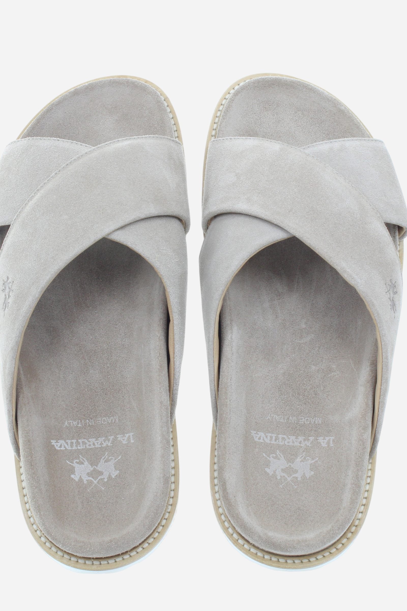 Men’s slides, lightweight and comfortable, featuring a suede upper that offers softness and refined aesthetics. The leather welt, stitched directly to the upper, highlights the craftsmanship and attention to detail. The model is enriched with a printed logo on the covered footbed and horse motif on the side strap. The ultra-light EVA sole ensures flexibility, cushioning, and freedom of movement, making these slides ideal for everyday comfort with a refined style. - Sand