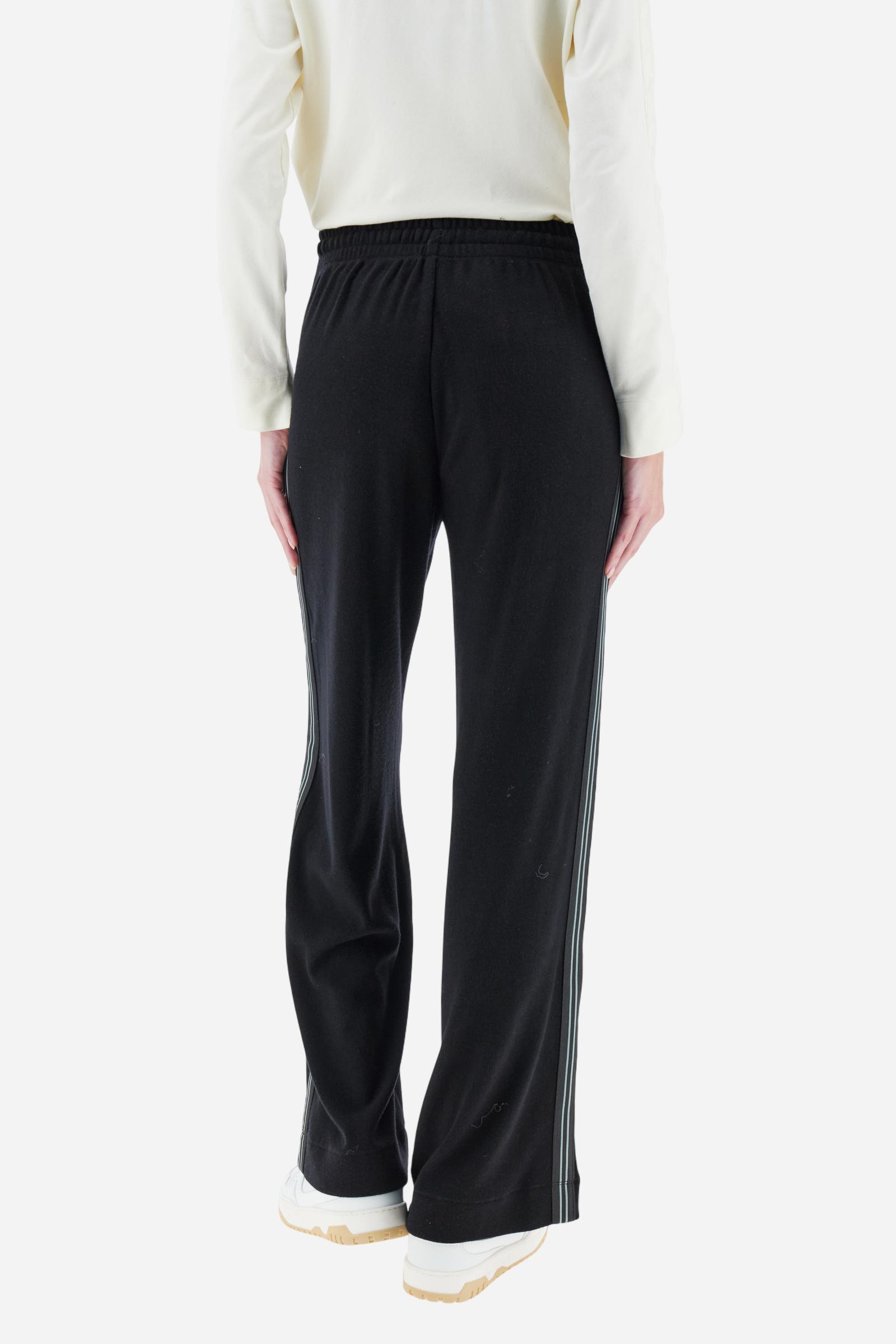 Women’s pants made of viscose-blend interlock fleece, soft and luxurious on the skin. Elastic waistband with adjustable drawstring ensures optimal comfort. Side pockets and bicolor striped tape along the sides complete the design. A small tonal embroidered logo enriches the front. Straight leg with slightly flared hem for a feminine, elegant twist in athleisure style. Model wears size 2. - Black