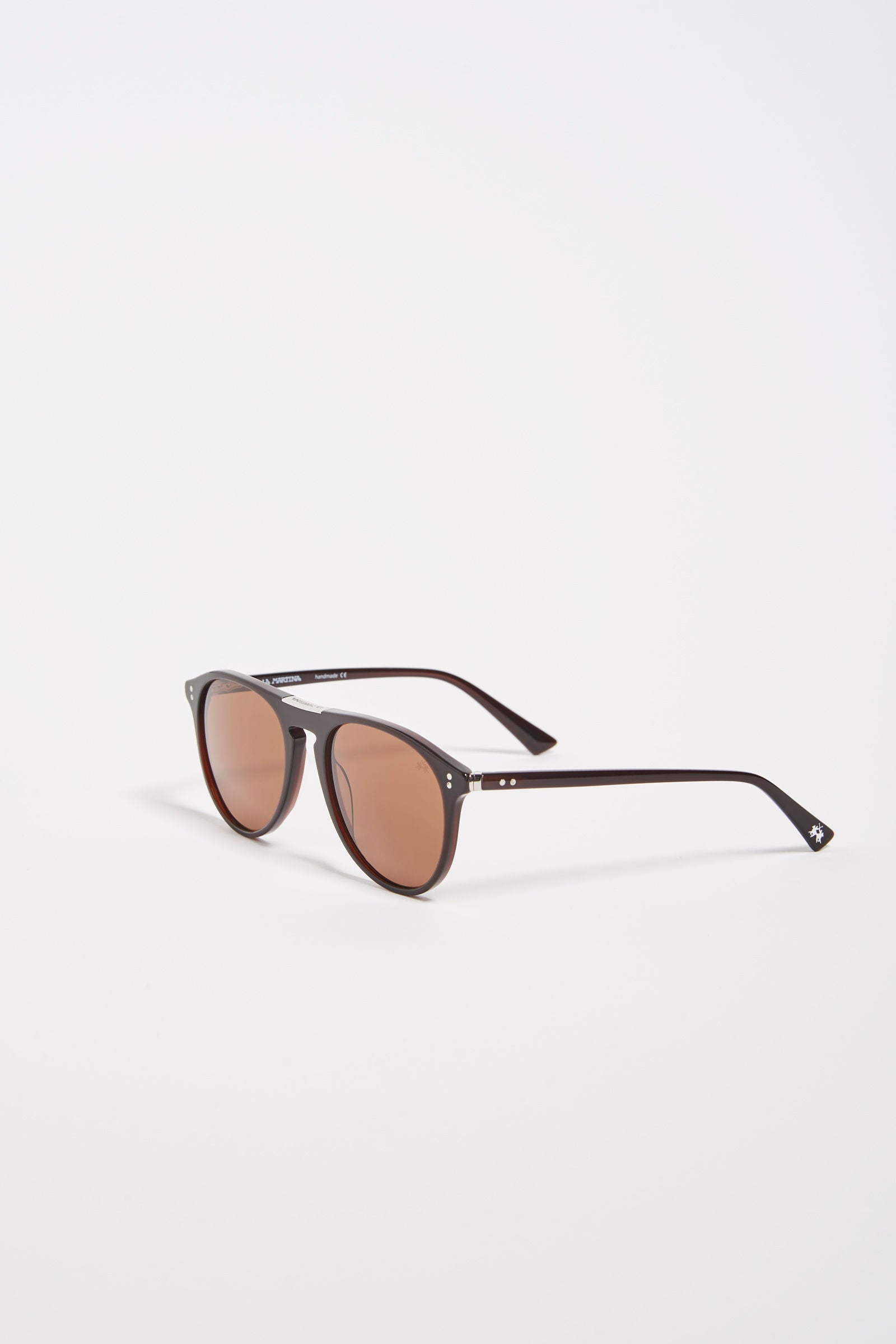 Men's acetate drop-shaped sunglasses. This classic style model features a small La Martina logo on the temple and on the front and lenses with internal blue anti-reflection. The details on the black frame make the eyewear particular, allowing you to wear it with any look and always be fashionable. - DARK BROWN