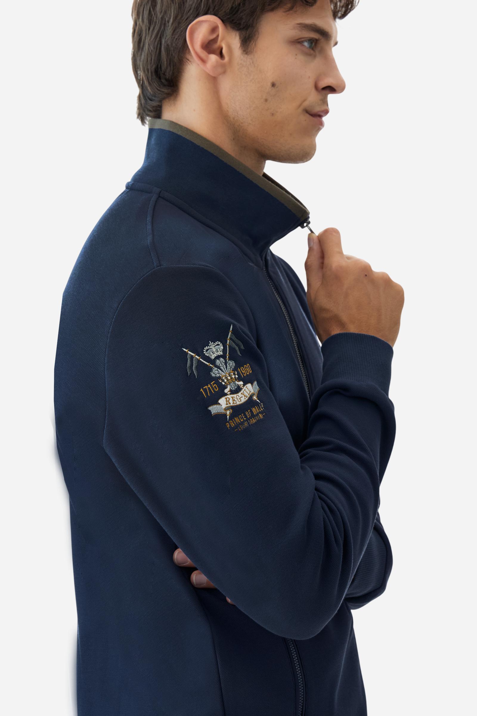 Men's long-sleeved, full-zip solid colour sweatshirt. Made of stretch cotton-blend piqué. Design with front opening fastened by a zip, high collar in two-tone ribbing. Solid colour ribbed cuffs and waistband. The small brand logo and Guards crest are embroidered in multi-coloured thread on the chest. On the right sleeve, there is another embroidery of a crest inspired by the British royal household. The regular fit silhouette is practical for everyday wear. The model is wearing a size L. - Navy