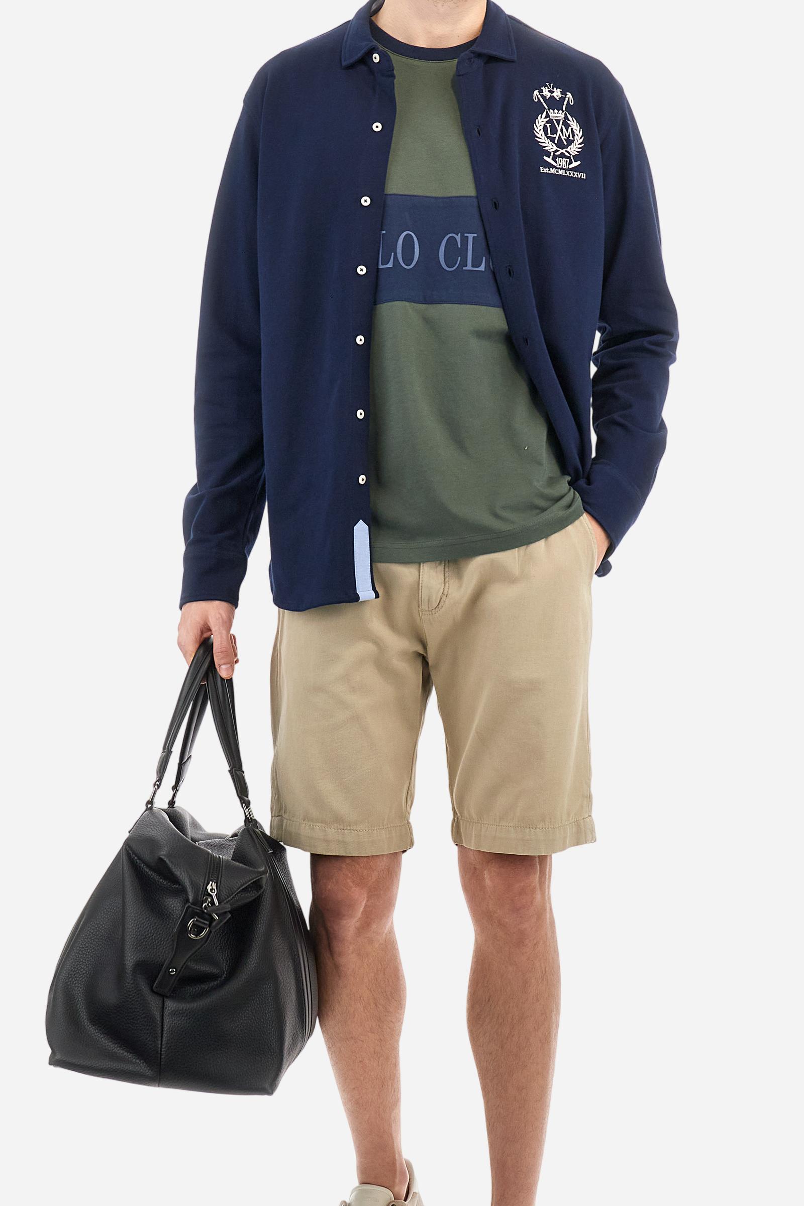 Men's plain long-sleeved shirt made from cotton piqué. It features an elegant spread collar and a seamless front opening, with no visible stitching. A graphic is embroidered on the chest, over the heart, in contrasting thread. Regular fit. The model is wearing a size L. - Navy