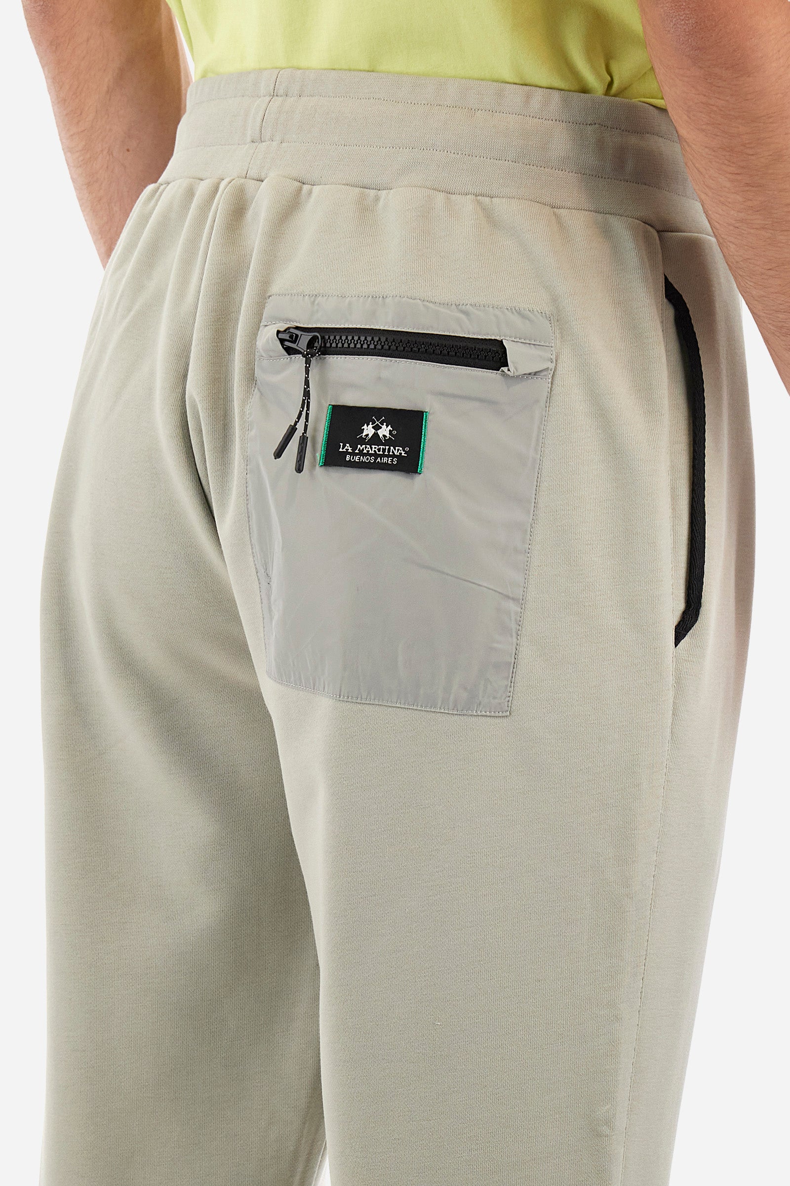 Men's single-colour jogging bottoms in a cotton sweat fabric. With a drawstring waist and double front pocket. With different shades at the bottom of the leg. On the back there is a pocket with a zip fastening featuring contrasting textures and colours. The logo is present on the tag sewn on the back pocket. The fit is regular. The model wears a size L. - Pussywillow Grey