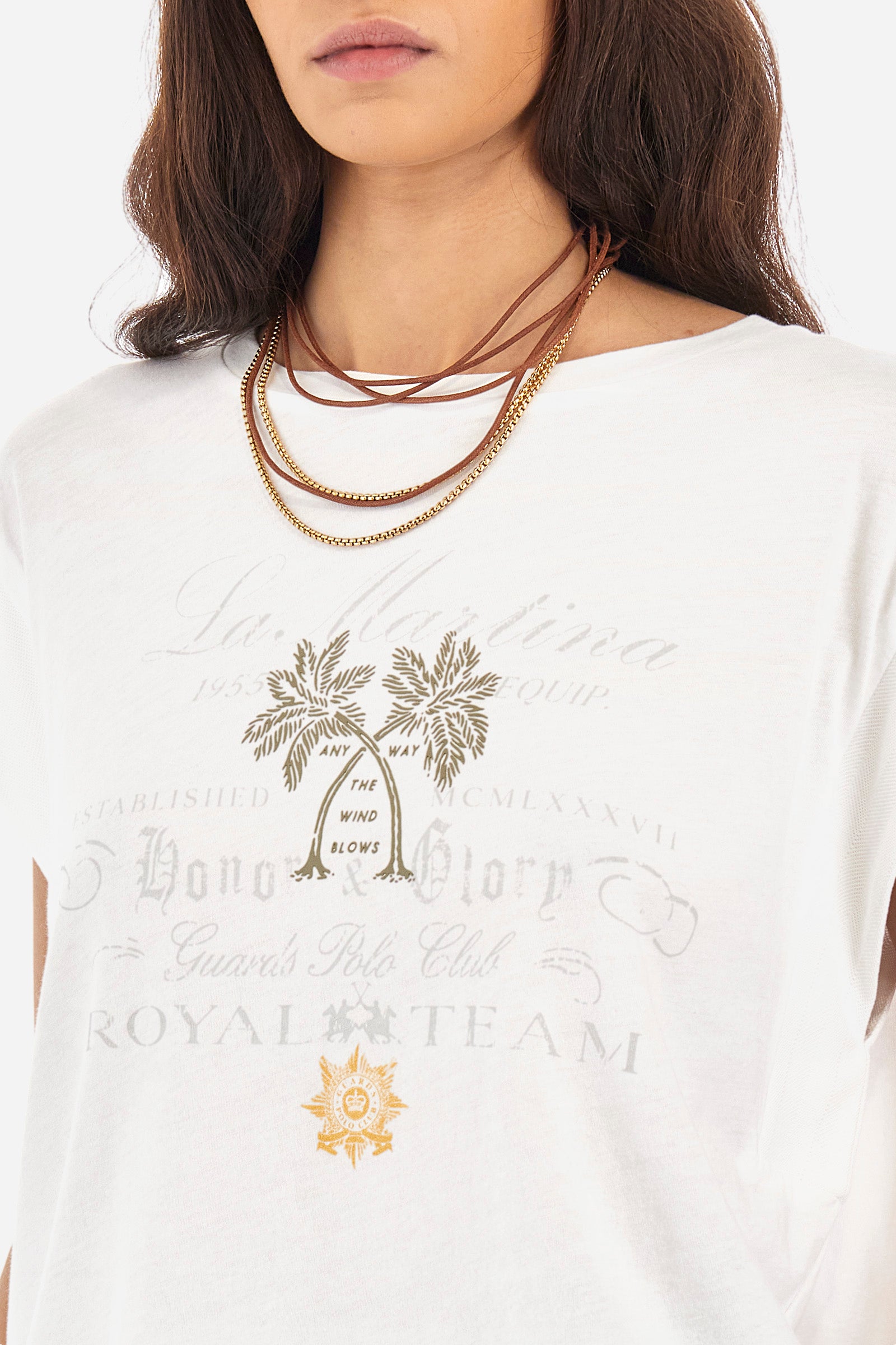 Women’s crew neck short-sleeved t-shirt in solid color, made of 100% cotton jersey. On the front we find an embroidered mini logo La Martina together with the symbol of the capsule collection Guards, in contrasting tone, which are accompanied by palm prints. Two mini side slits. The fit is regular. The model wears a size 2. - Optic White