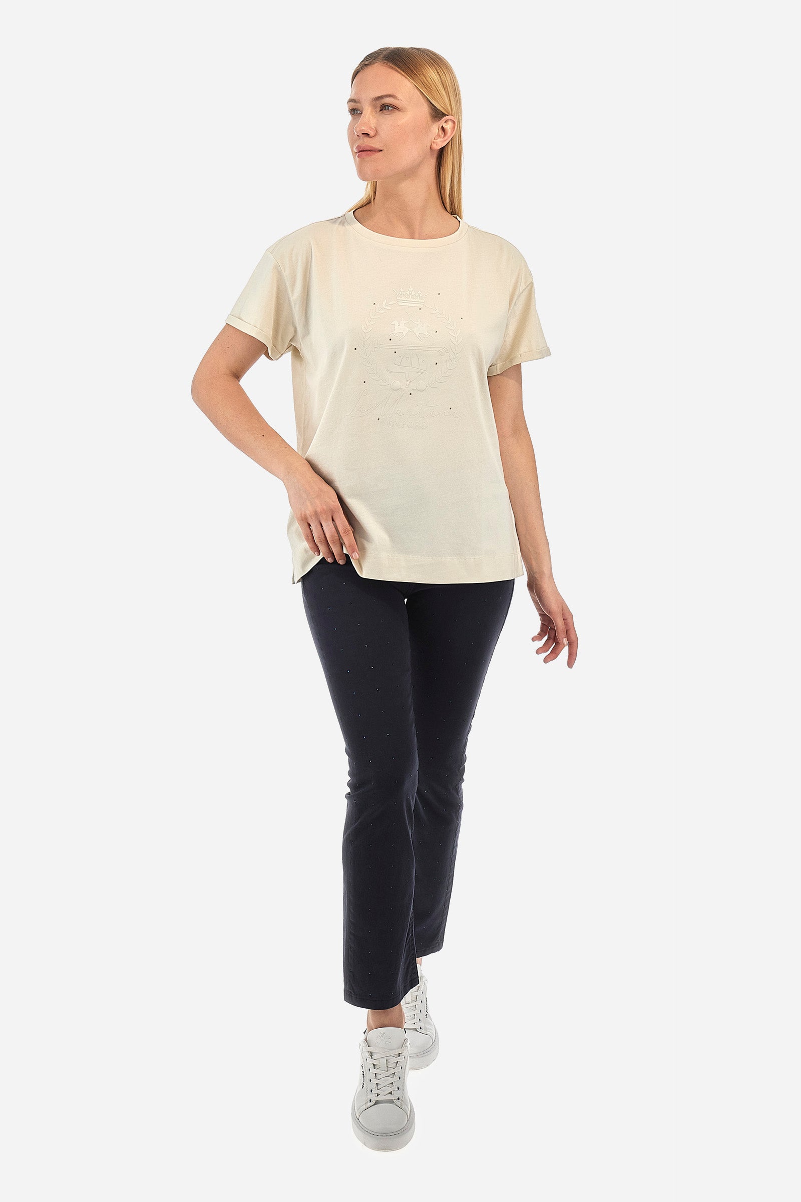 Women's short-sleeved T-shirt with a crew neck in a single colour from the Polo Academy line. Made of 100% cotton. There is a slight turn-up on the sleeve. The front features the La Martina logo and lettering and some of the symbols of the Polo Academy line, all tone on tone. The T-shirt is embellished with all-over tone-on-tone rhinestone applications. The fit is regular. The model wears a size 2. - Bone White