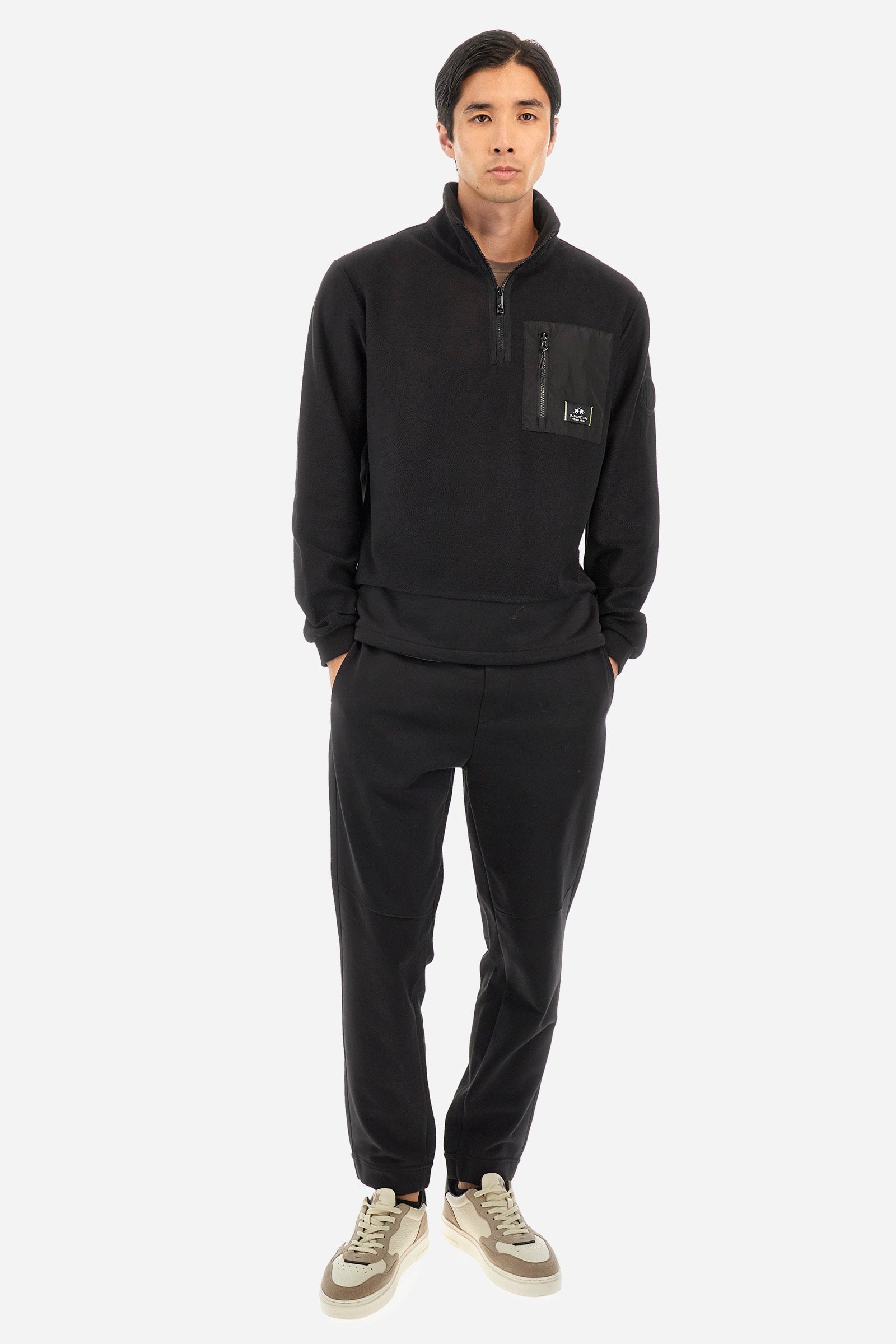 Men's single-colour jogging bottoms in a cotton sweat fabric. With a drawstring waist and double front pocket. With different shades at the bottom of the leg. On the back there is a pocket with a zip fastening featuring contrasting textures and colours. The logo is present on the tag sewn on the back pocket. The fit is regular. The model wears a size L. - Black