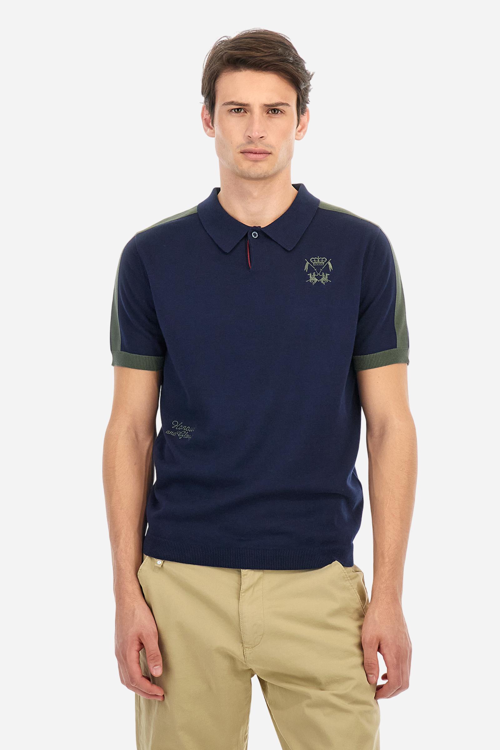 Men's two-tone short-sleeved knitted polo shirt made of 100% cotton. The cuffs are contrasting, while the waistband is in the same tone, but both are ribbed. The applied bands on the sleeve and shoulders are knitted in a contrasting colour. Contrasting details are present on the neck opening and inside the collar as a decorative motif. Small embroidered lettering on the front. The logo is embroidered in a contrasting colour on the chest, left side. The fit is regular. The model is wearing a size L. - Navy