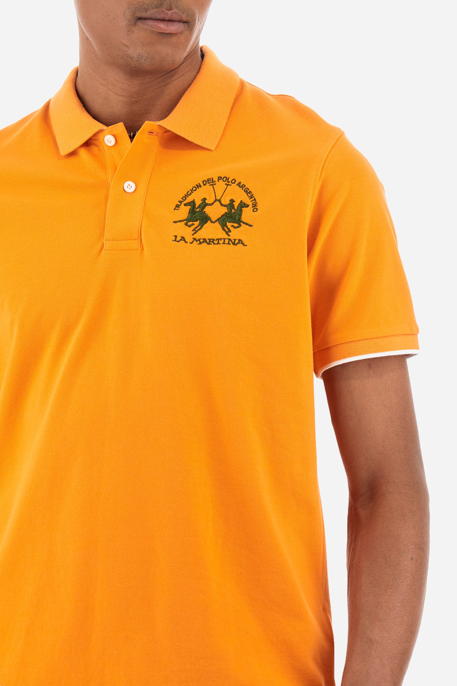 Men’s polo with short sleeves, regular fit. Made of stretch pique cotton. Classic model, with large embroidered logo in contrasting tone on the chest and profiled sleeve edges. The collar is accompanied by the writing La Martina, in contrasting tone. Ideal if worn with a denim collection. The model wears a size L. - Celosia Orange