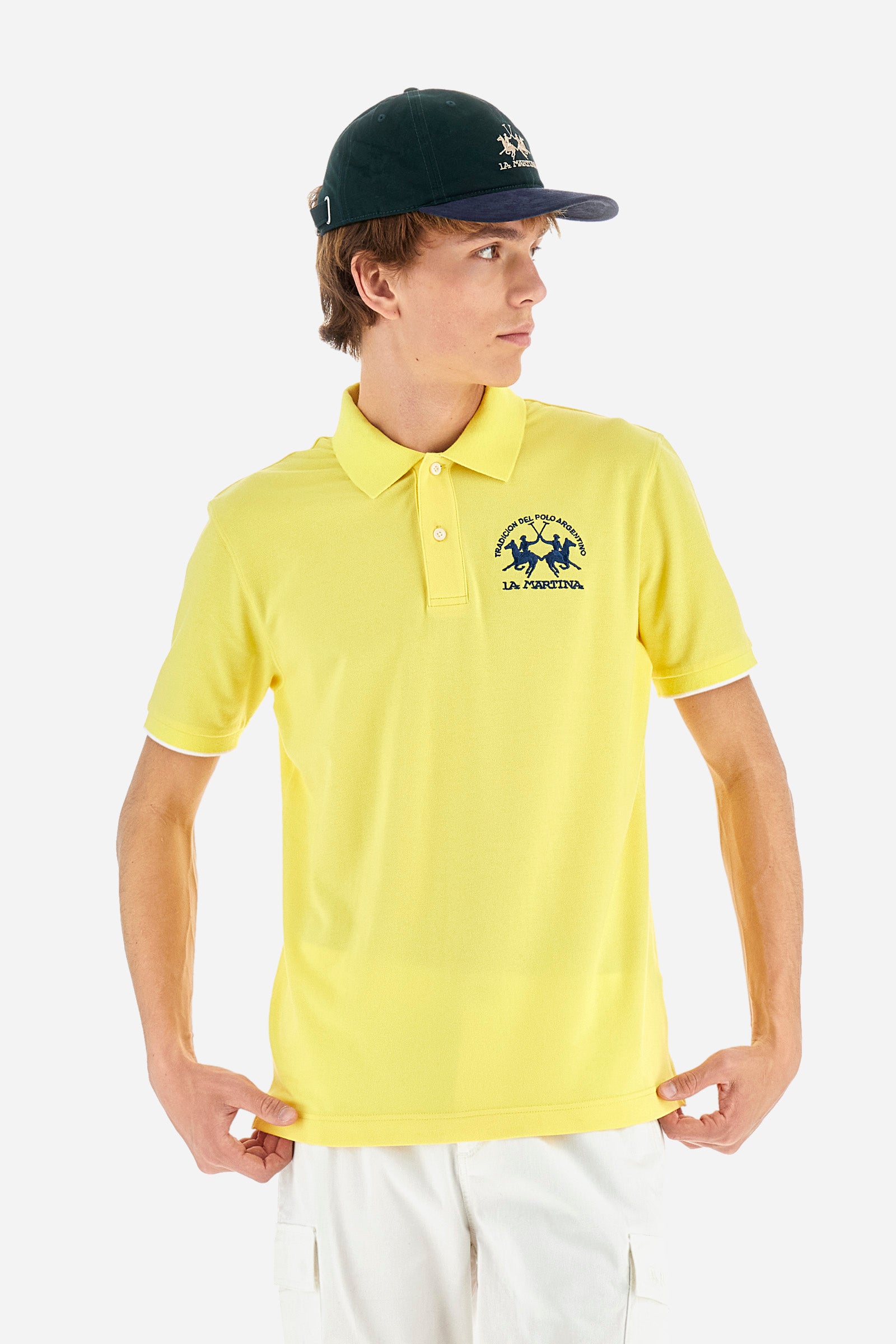 Men's plain short-sleeved polo shirt made from stretch piqué. Featuring a two-button fastening and a ribbon on the inside collar in contrasting coloured grosgrain. The collar and cuffs are in matching rib knit, with the undercollar also in rib knit but in a contrasting colour. The large logo is embroidered on the chest, left side with contrasting coloured thread. The undercollar features a print of the La Martina lettering in a contrasting colour. Regular fit. The model is wearing a size L. - Aurora