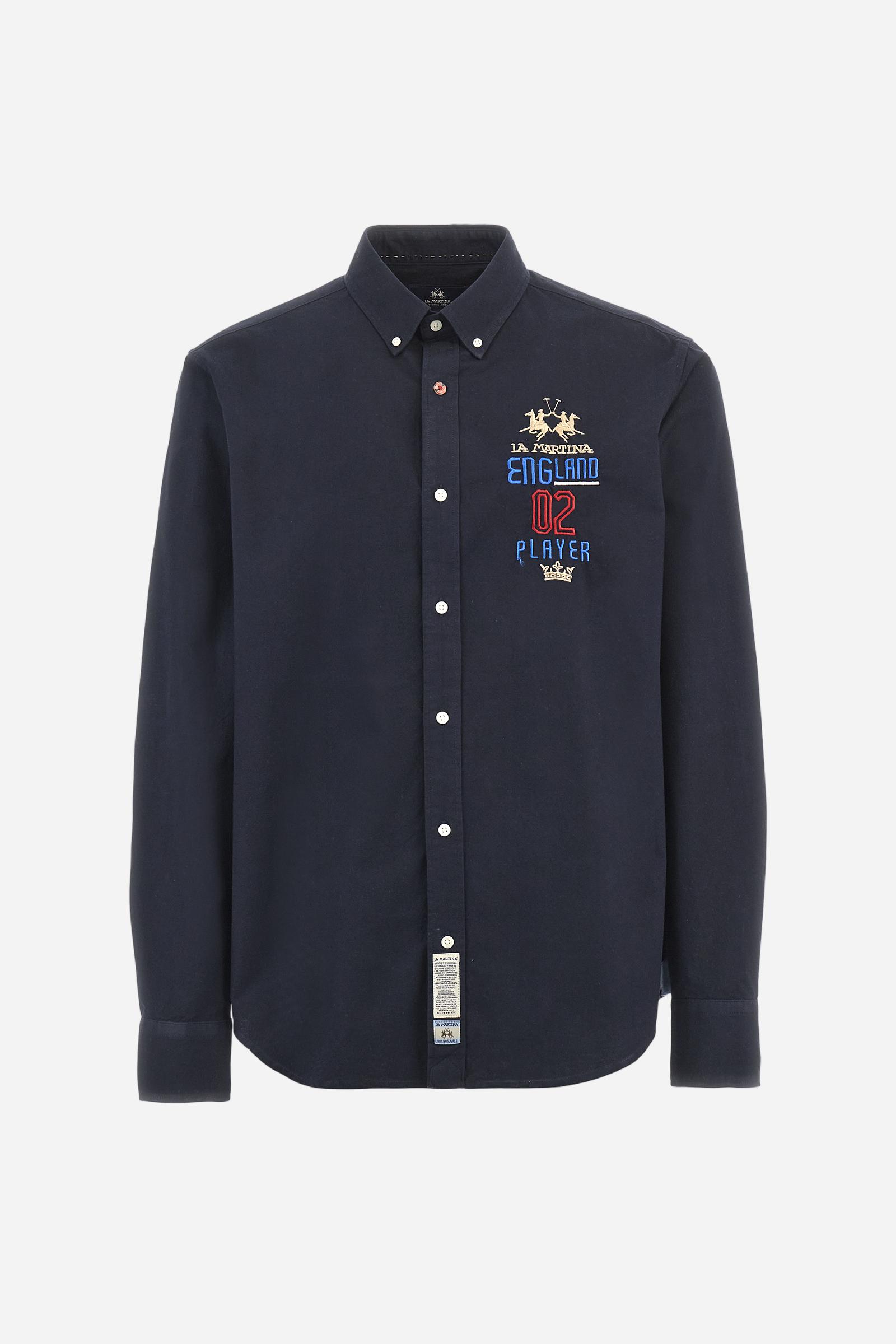 Men's long-sleeved plain shirt made from 100% Oxford cotton. The button-down collar is finished with a second button printed with the English flag. The multicoloured embroidery on the chest, over the heart, includes lettering, numbers and the logo, which add a distinctive touch. Regular fit. The model is wearing a size L. - Navy