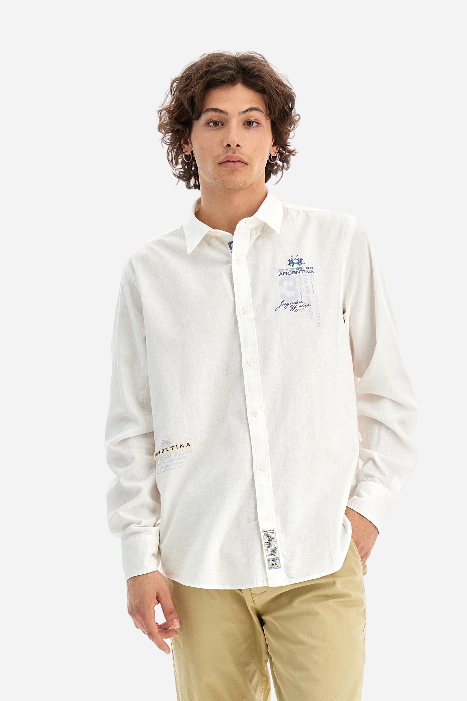 Men's plain long-sleeved shirt made from cotton and linen canvas. Featuring a button-down collar and sleeve openings embellished with contrasting fabric details. The graphic on the chest, over the heart, is created using a combination of embroidery and printing techniques to add a distinctive touch. On the side, at the front, there is a ribbon embroidered with the word Argentina, topped with a print. Regular fit. The model is wearing a size L. - Optic White