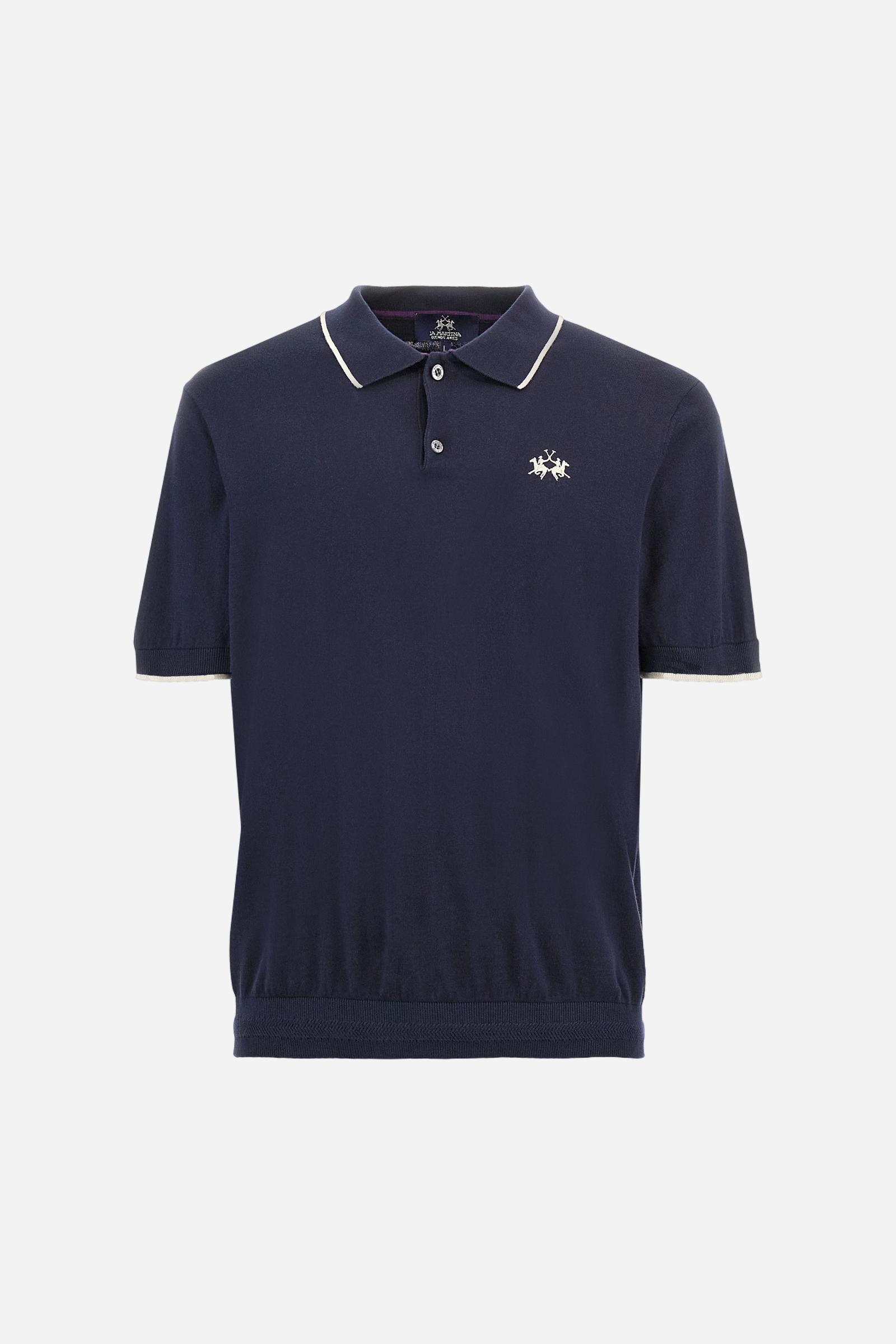Single-colour men's polo shirt with short sleeves. Made of knitted cotton yarn. Two-button fastening and ribbed collar with contrasting stripes on the bottom. The cuffs of the sleeves are ribbed, as is the band at the bottom, which is embellished in the centre with a band featuring a herringbone stitch. A contrasting coloured jersey ribbon is applied to the inside of the collar. The logo is embroidered on the left side of the chest in contrasting thread. Regular fit. The model is wearing a size L. - Navy