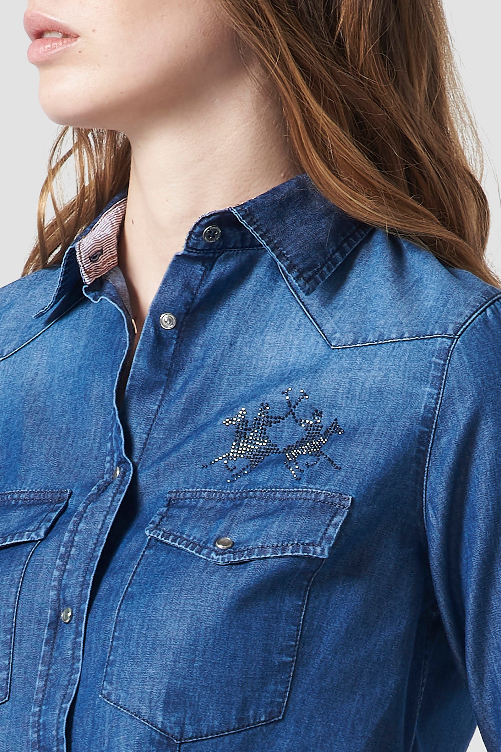 Women's plain-coloured, long-sleeved shirt in soft stretch cotton fabric featuring a classic cutaway collar. The classic fit is suitable for any figure as it remains relaxed and not too tight. Rhinestone La Martina logo on the front. Perfect for wearing with a pair of the collection's jeans or elegant trousers, day or night. The model is 174 cm tall and wearing a size S. - Medium Indigo Denim