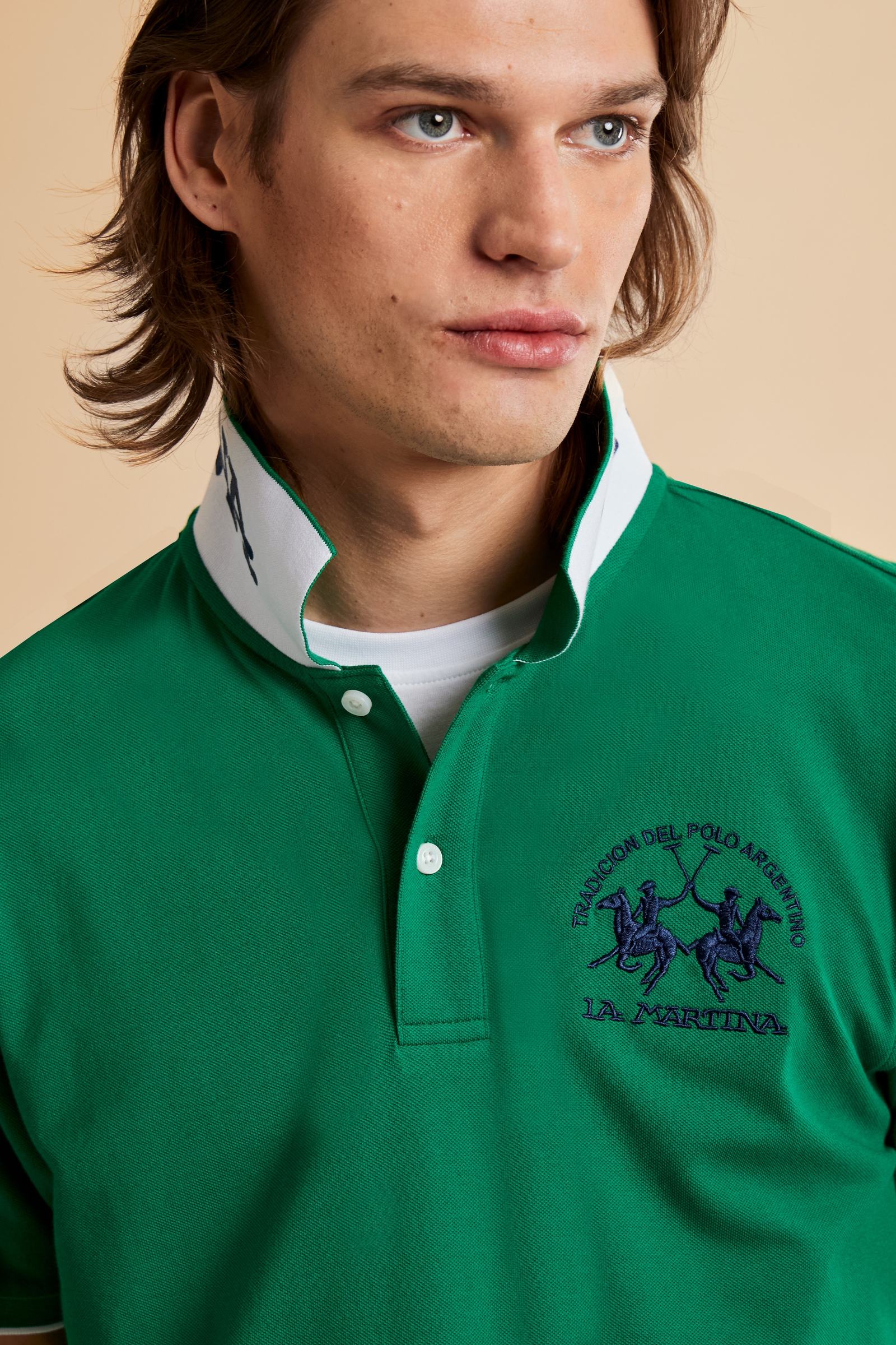 Men's short-sleeve polo shirt made from solid-color stretch piqué fabric. The model features a two-button front placket with ribbed collar and cuffs in matching tone. An iconic design of the brand, it stands out for the large embroidered team logo in contrasting color on the chest and the bold brand print under the collar in contrasting color. The regular fit ensures comfort and versatility for everyday wear. The model is wearing size L. - Amazon