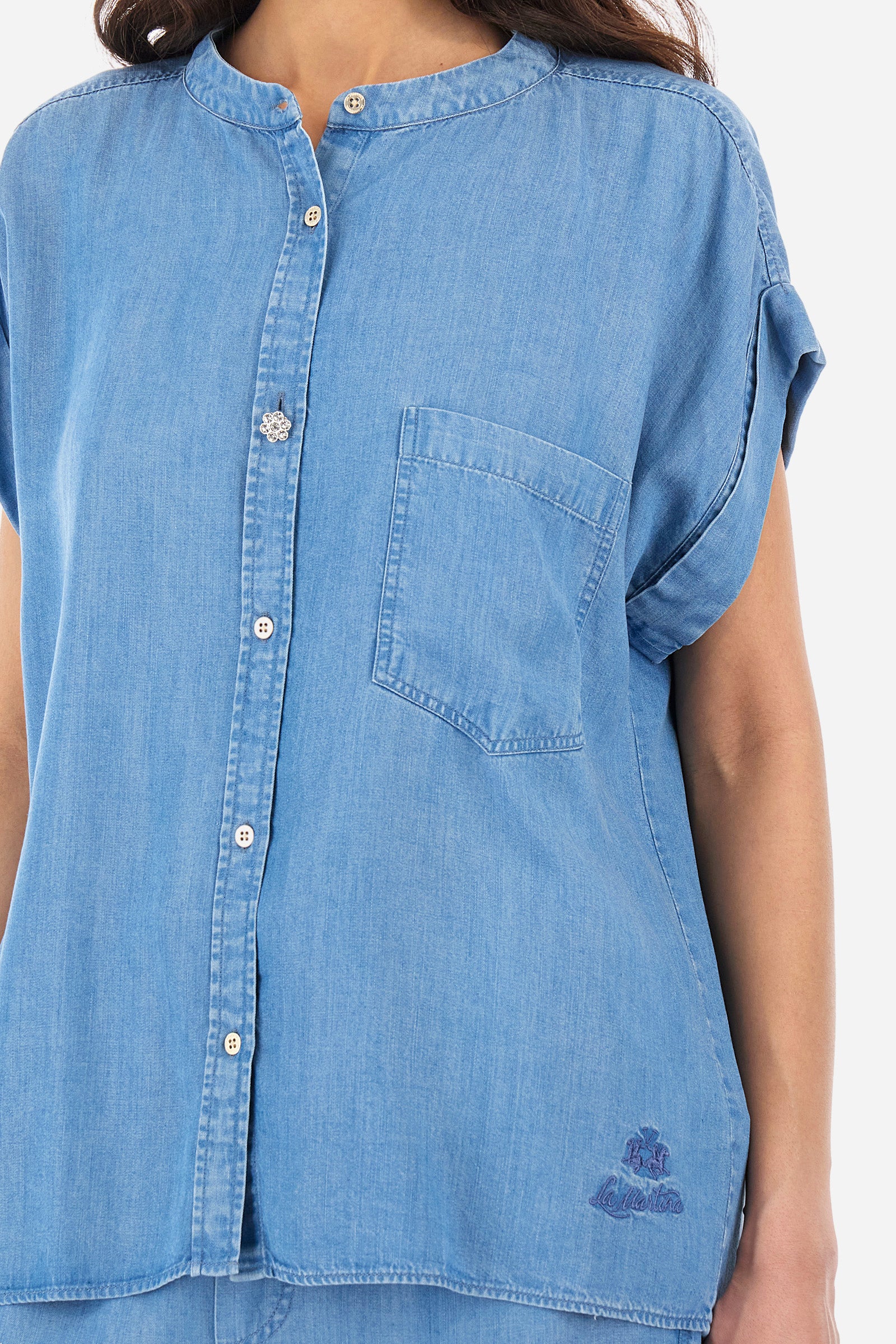 Women's short-sleeved denim shirt, made of ecological fabric. Mandarin collar. There is an open pocket on the chest. Featuring a jewel button. The front features the logo and "La Martina" lettering. The fit is regular. The model wears a size 2. - Medium Indigo Denim