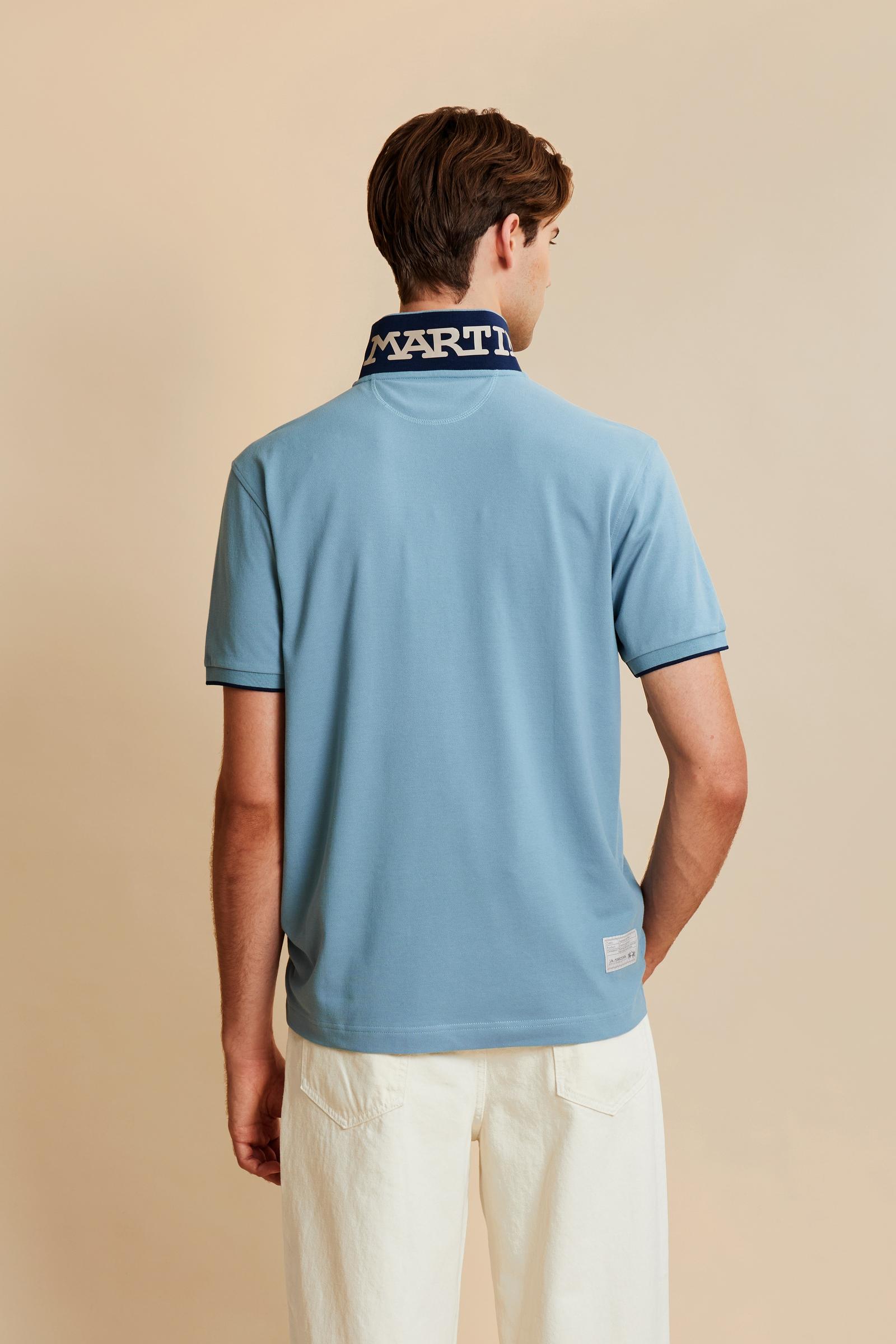 Men's short-sleeve polo shirt made from solid-color stretch piqué fabric. The model features a two-button front placket with ribbed collar and cuffs in matching tone. An iconic design of the brand, it stands out for the large embroidered team logo in contrasting color on the chest and the bold brand print under the collar in contrasting color. The regular fit ensures comfort and versatility for everyday wear. The model is wearing size L. - Stone Blue
