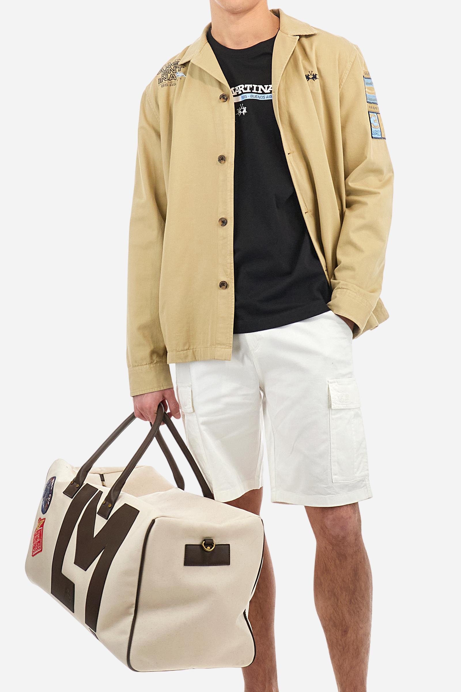 Men's single-colour long-sleeved overshirt made of 100% cotton slub twill. Bowling collar and jacket opening with inside placket, fastening with imitation horn buttons.On the shoulder and chest the embroidery is in tone with the garment, Argentina lettering embroidered on one shoulder. There are several patches applied on the left sleeve. A tone-on-tone logo is embroidered on the front. Regular fit. The model is wearing a size L. - Twill