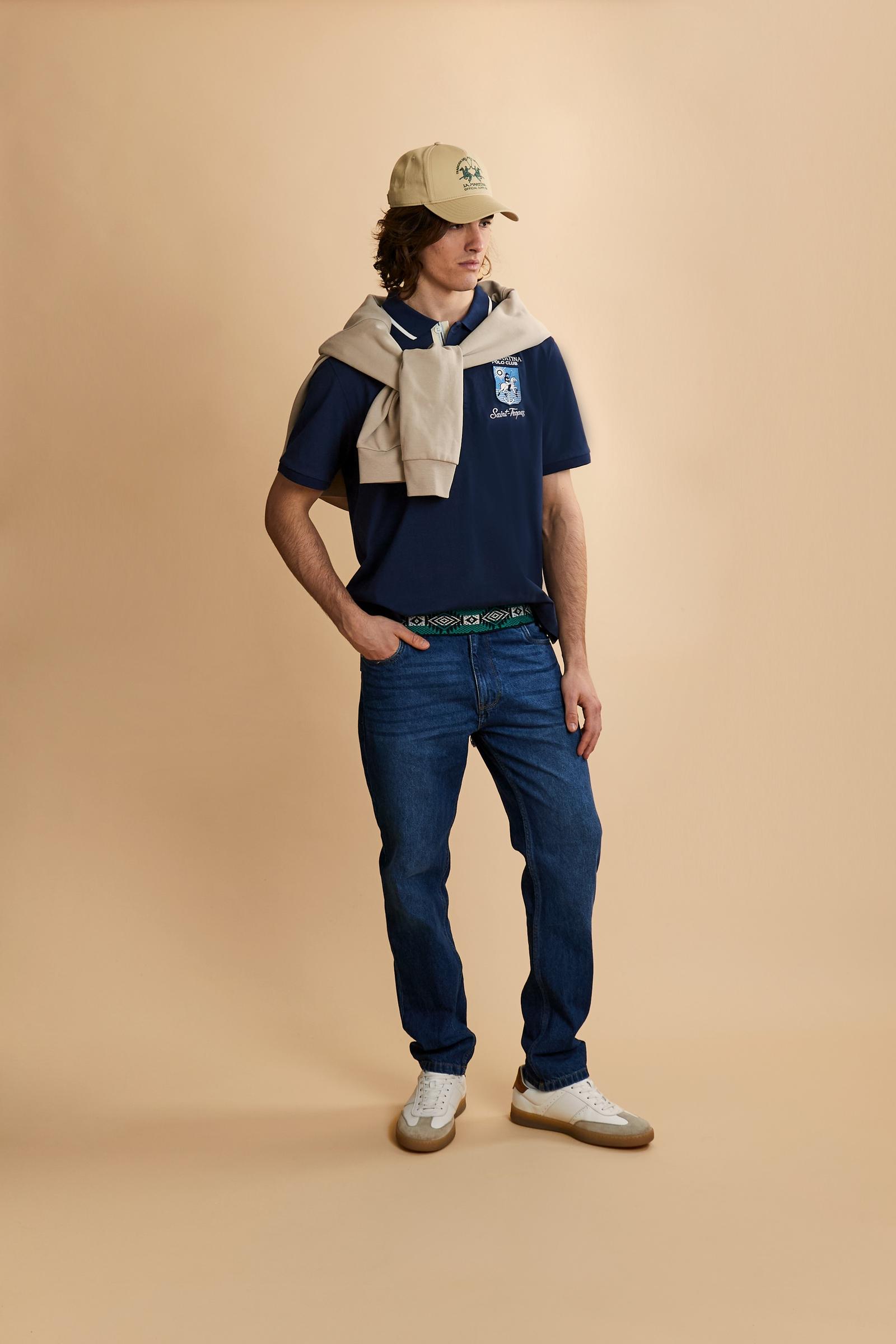 Men's short-sleeve polo shirt made from heavy-weight cotton jersey in solid color. The model features a front opening in contrasting jersey with vertically embroidered chain stitching. The collar and cuffs are ribbed with contrasting edge detail. The design is enriched with an embroidered crest on the chest dedicated to Saint Tropez and the iconic two polo players logo embroidered on the back. The fit follows modern trends with a slightly oversized silhouette, dropped shoulders and a relaxed shape. The mode