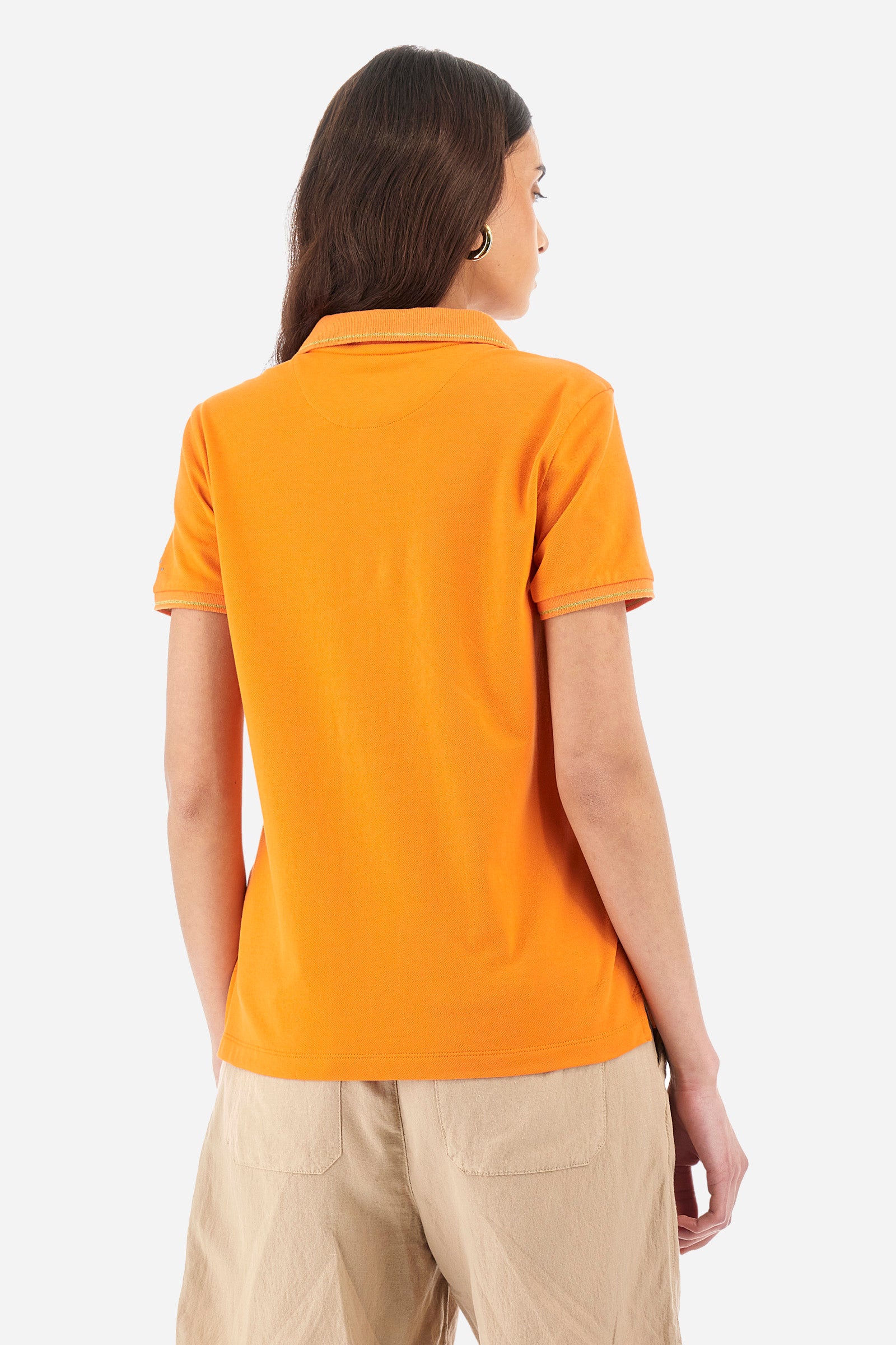Women’s polo with short sleeves in solid color, made of stretch cotton. 5-button closure. Collar and crew sleeves profiled and ribbed. Side slits. Under the collar there is the inscription "La Martina". The logo is embroidered on a sleeve and embellished with the application of some rhinestones. The fit is regular. The model wears a size 2. - Celosia Orange