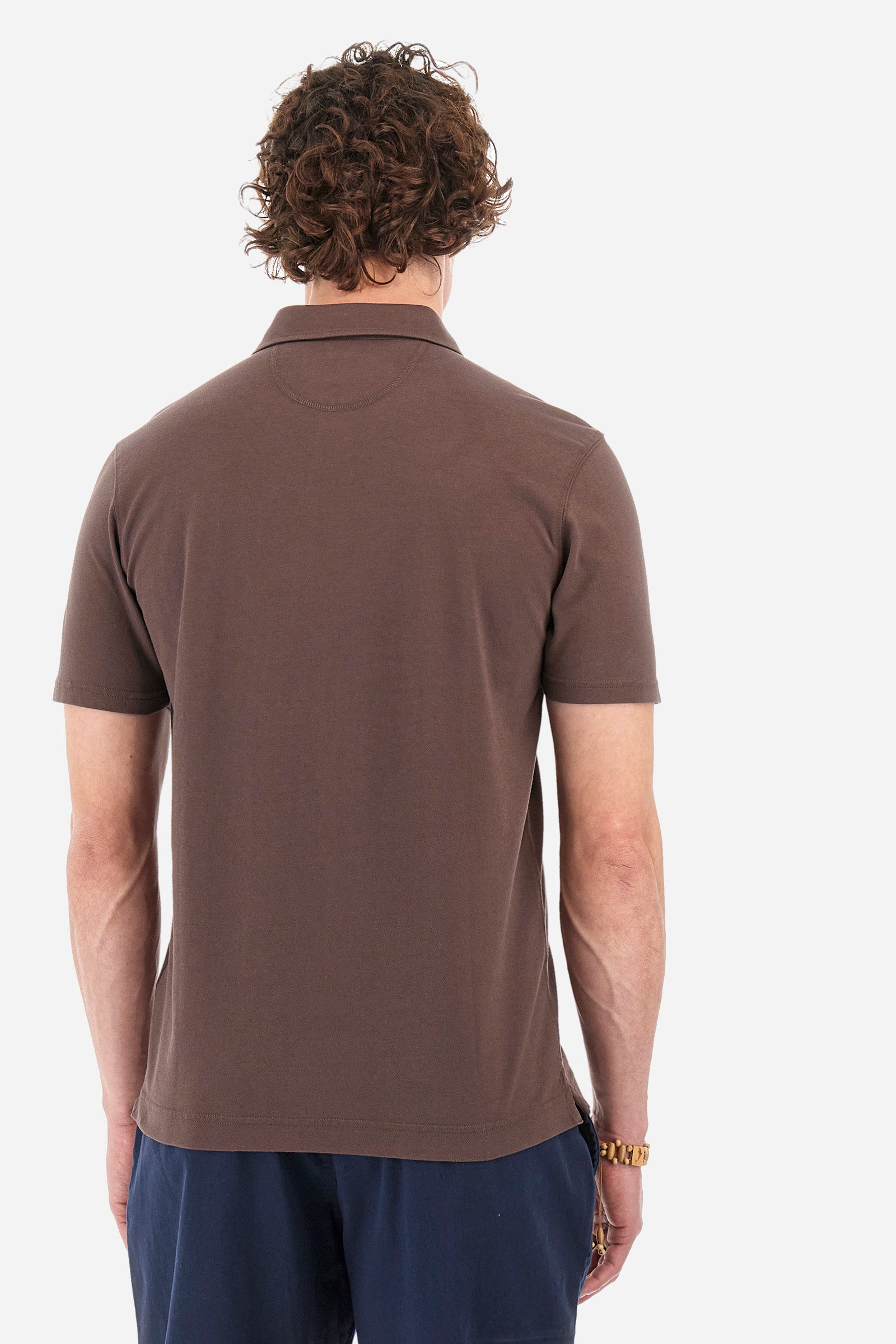 Men's short-sleeved single-colour polo shirt in elasticated cotton. Two-button fastening. Pointed collar. On the front we find copper-coloured lettering and a large logo. On one of the sleeves there is a symbol representing the Guards line. The fit is regular. The model wears a size L. - French Roast