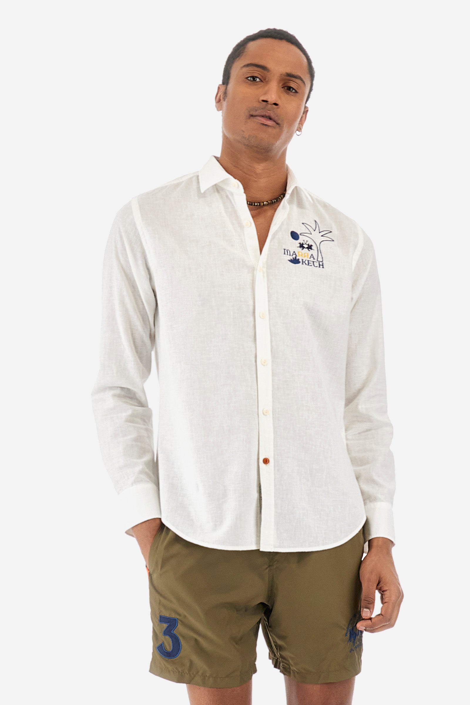 Men's single-colour long-sleeved shirt in cotton and linen. Pointed collar. With buttoned cuffs. A small logo, a palm tree and some lettering are embroidered on the front. The fit is regular. The model wears a size L. - Optic White