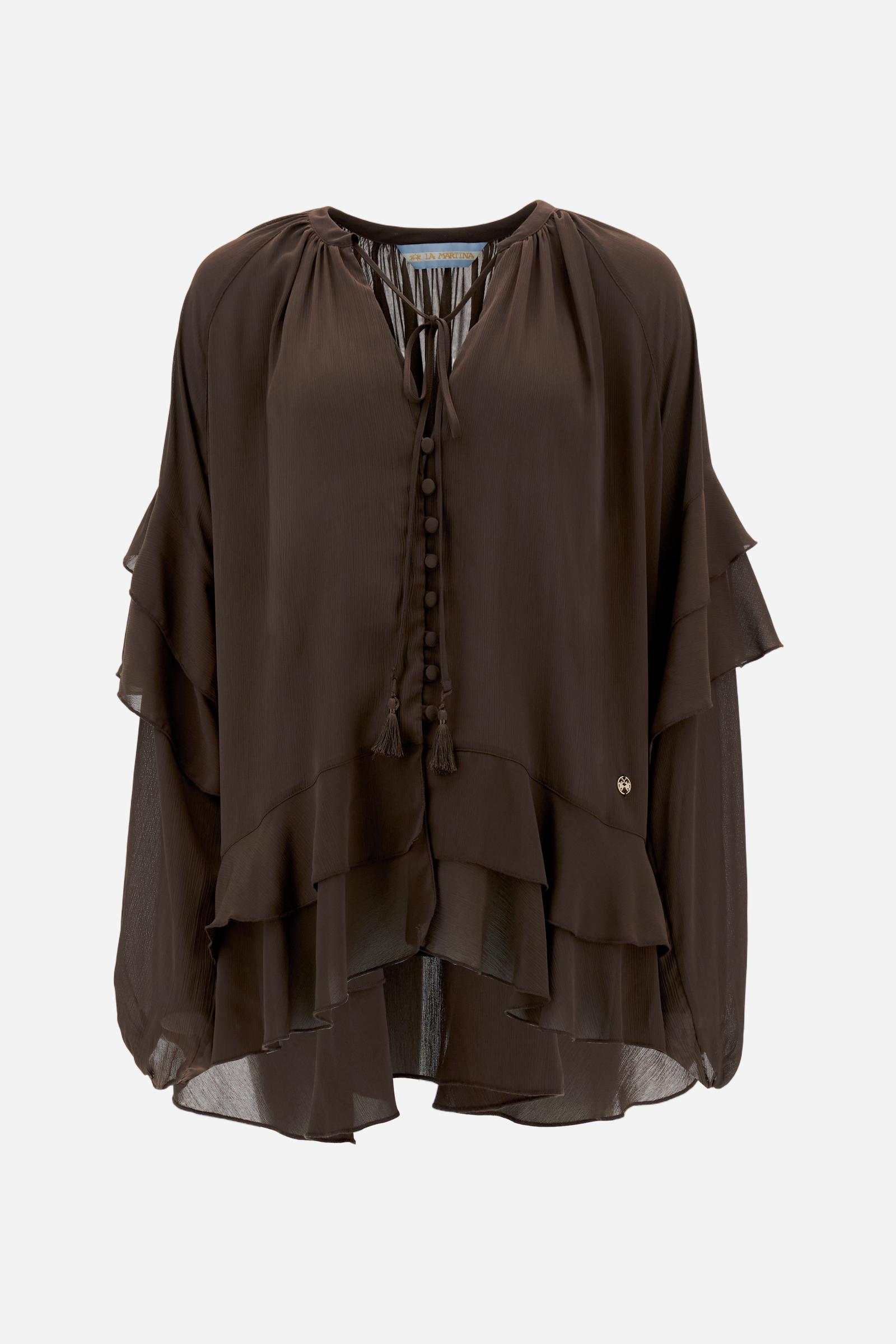 Women’s blouse with long sleeves in solid-colour chiffon with mandarin collar and V-neckline closed by ties and covered buttons. Loose fit with longer back and wide ruffles on sleeves and hem. The logo appears on a small golden metal plate applied to the front hem. The model wears size 2. - Java