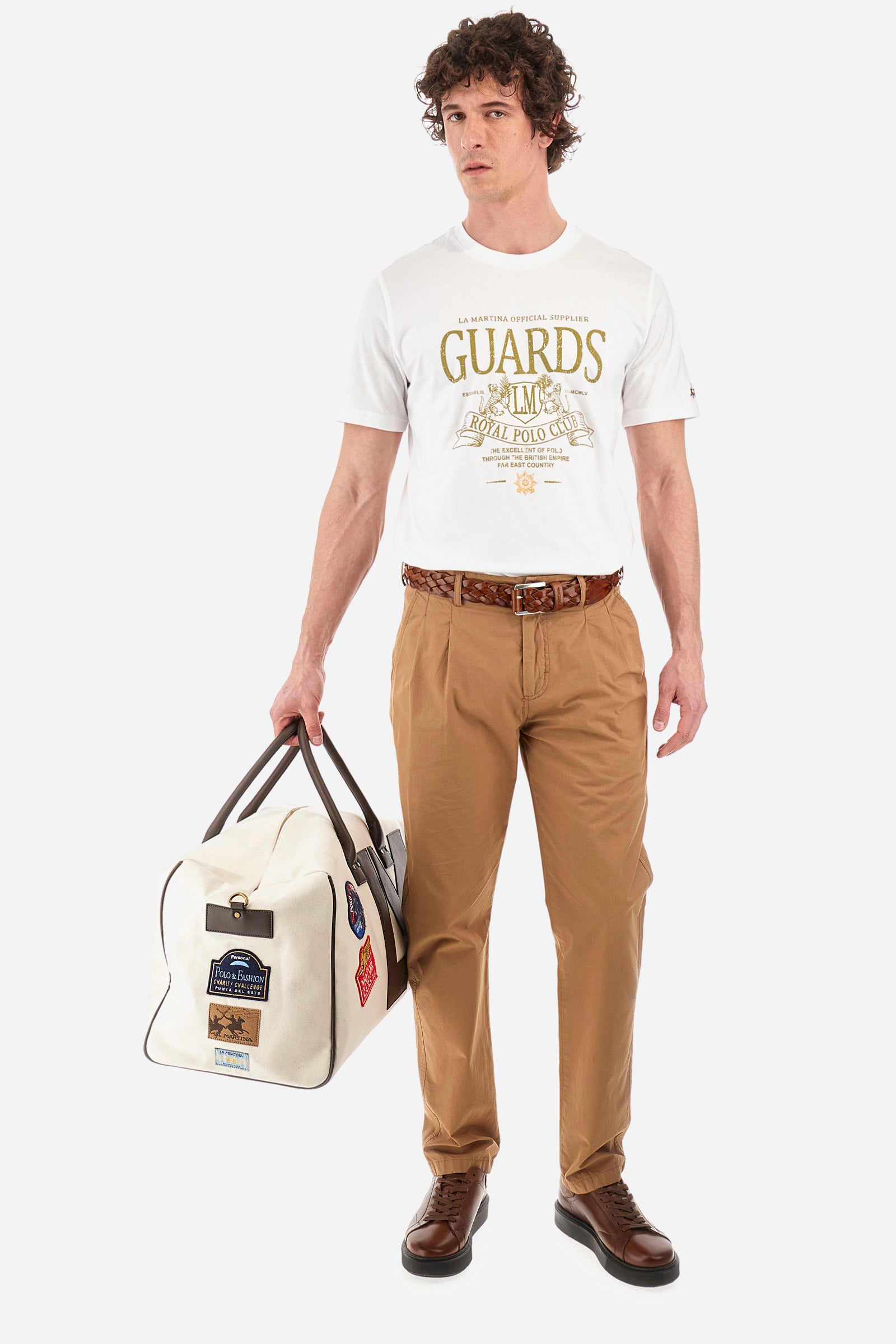 Men's single-colour chinos in 100% cotton. With belt loops, zip and button fastening. Darts on the front. There are two open front pockets and two closed back pockets with a classic button fastening. There is a logo with a patch sewn onto the reverse. The fit is regular. The model wears a size 33. - Tobacco Brown