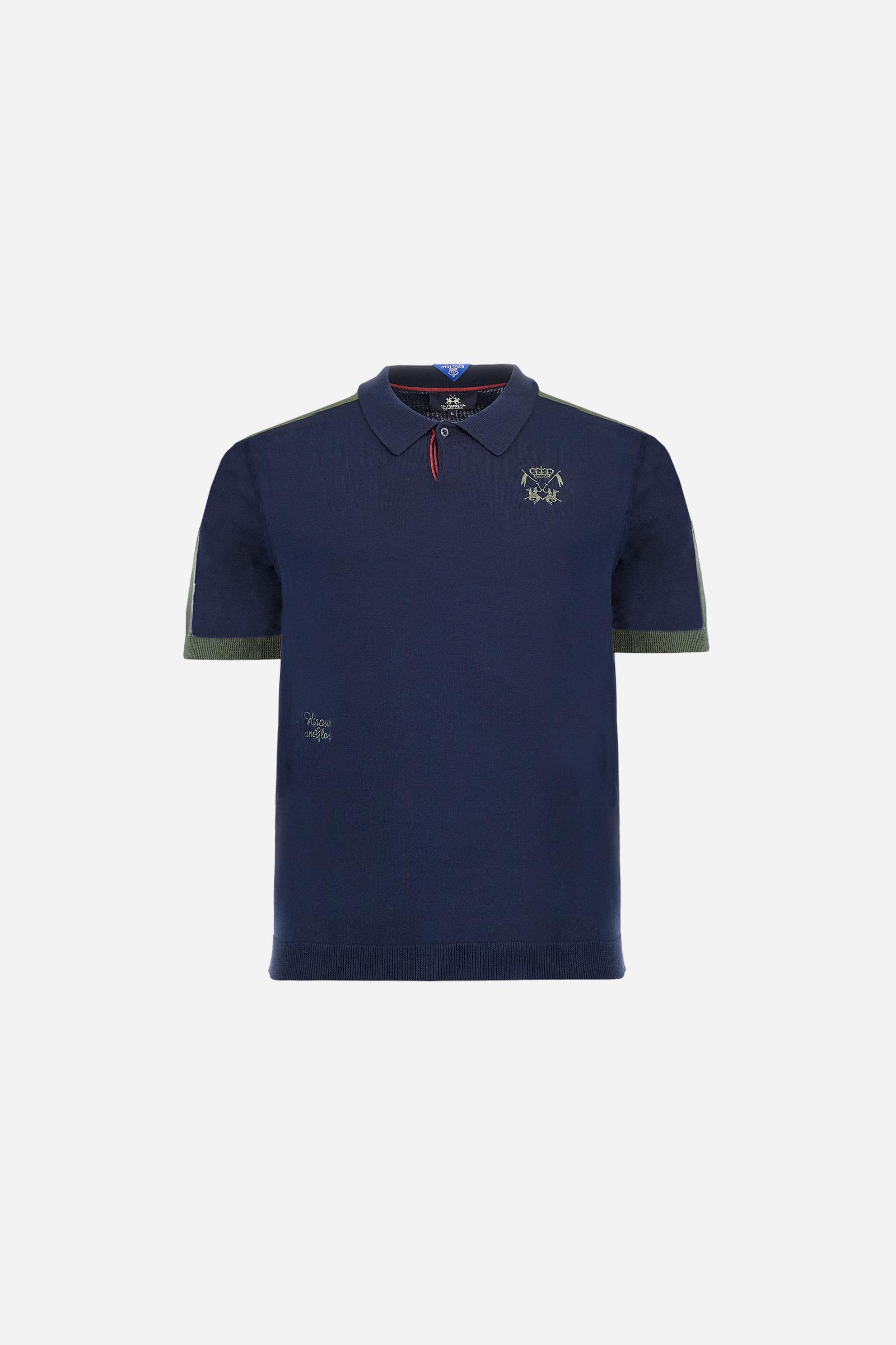 Men's two-tone short-sleeved knitted polo shirt made of 100% cotton. The cuffs are contrasting, while the waistband is in the same tone, but both are ribbed. The applied bands on the sleeve and shoulders are knitted in a contrasting colour. Contrasting details are present on the neck opening and inside the collar as a decorative motif. Small embroidered lettering on the front. The logo is embroidered in a contrasting colour on the chest, left side. The fit is regular. The model is wearing a size L. - Navy