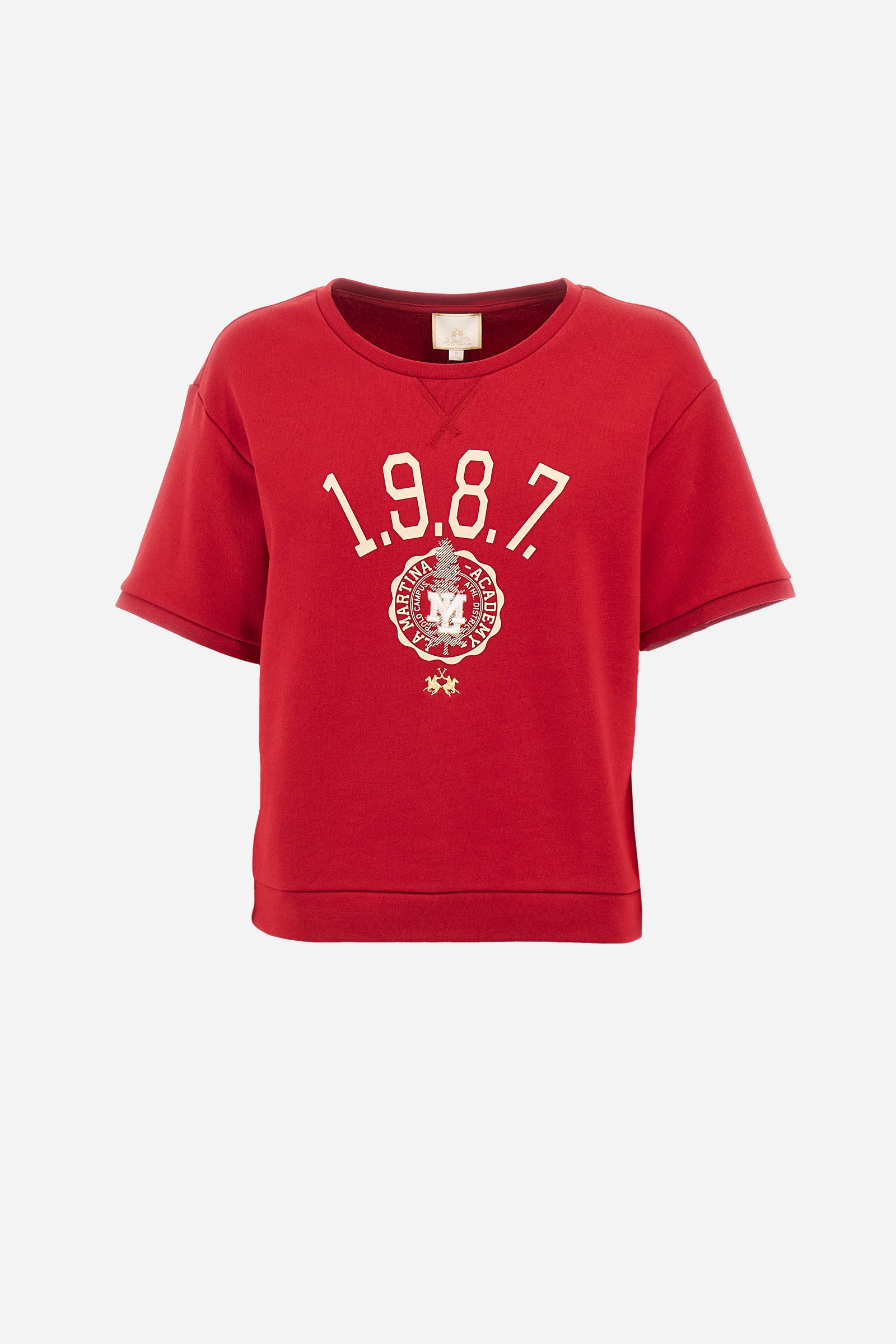 This women's cotton-blend short-sleeved crew-neck sweatshirt in a regular fit from the Polo Academy line is a comfortable choice for any occasion. The solid colour with La Martina 1987 print and logo on the front add a touch of style to your daily outfit. Thanks to the 5 buttons on the back, this sweatshirt is also practical and functional. Ideal for those looking for a versatile and quality garment. The model is 174 cm tall and wears a size 2. - Barbados Cherry