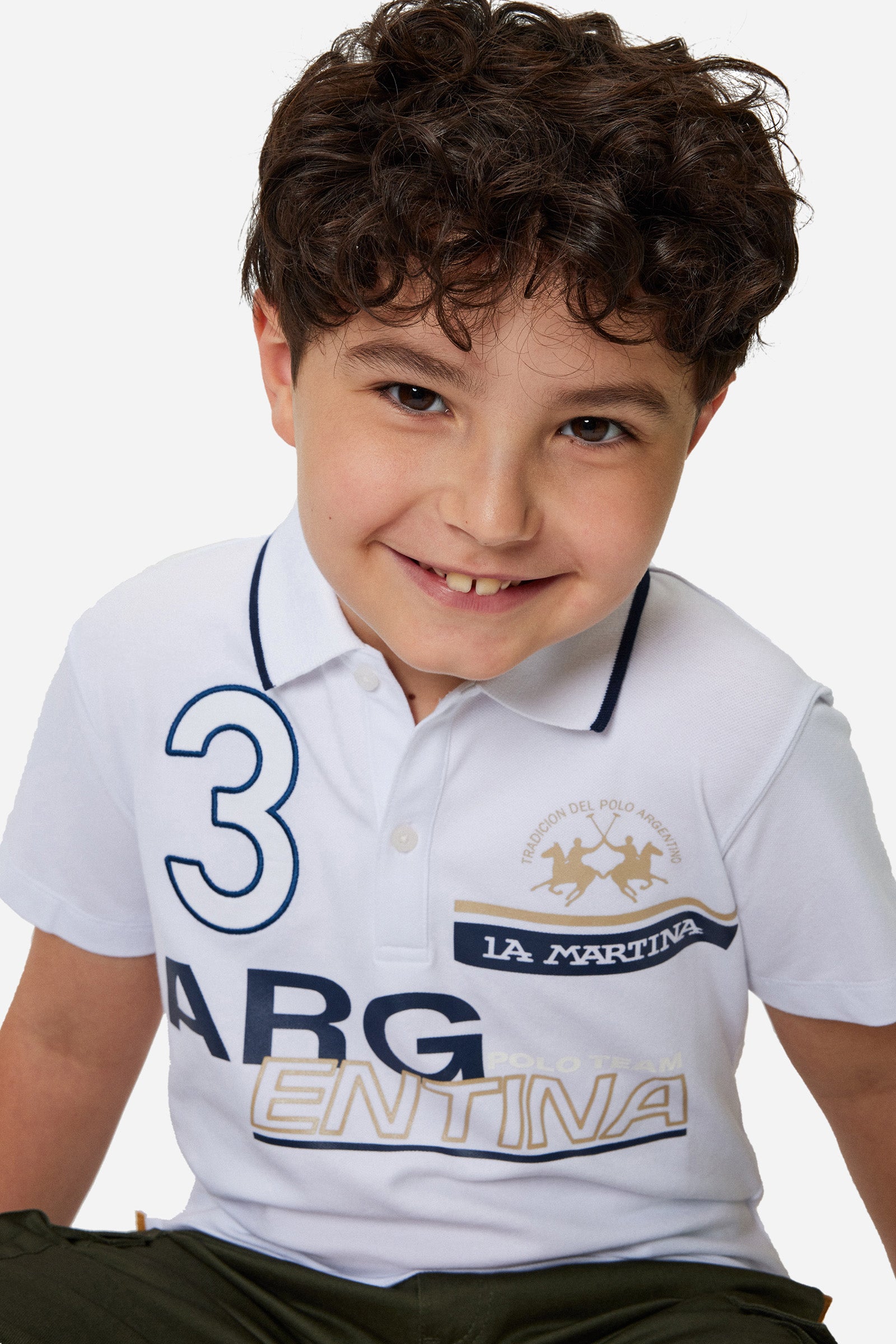 Boys' single-colour polo shirt made of pique cotton. Two-button fastening. Profiled collar with contrasting colour thread. There are various embroideries and rubberised prints on the front of the garment. The logo is on the chest, left side. - Optic White