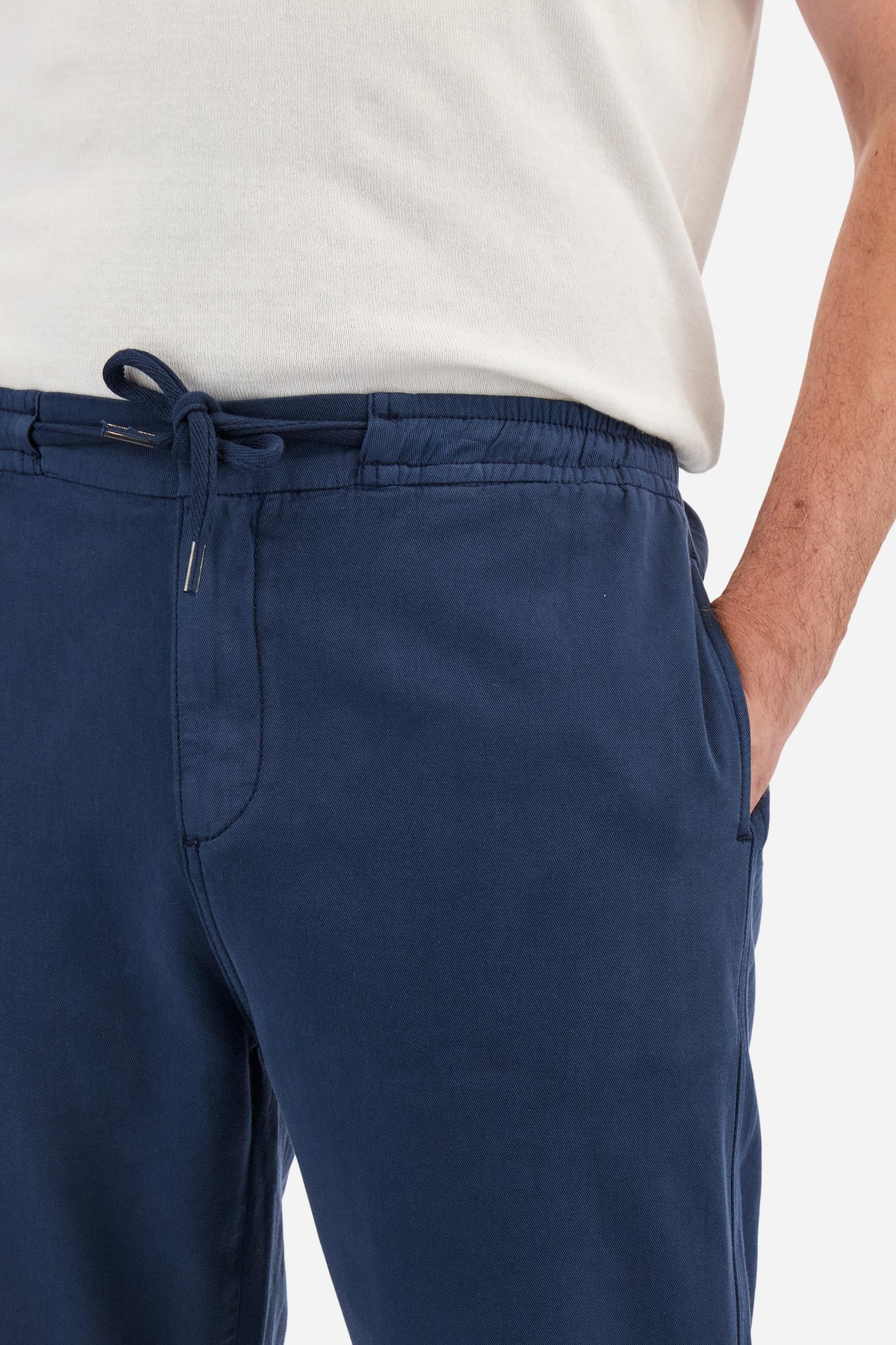 Men's plain straight-cut trousers, made of linen and cotton canvas. Featuring a waist belt at the back and on the sides with elasticated external drawstring for adjustment. The front opening also has a faux horn button on the belt and a zip. Double welt pocket inserted into the sides. There are two additional welt pockets on the back. The logo is featured on the woven label sewn above the right back pocket. Regular fit. The model is wearing a size L. - Navy