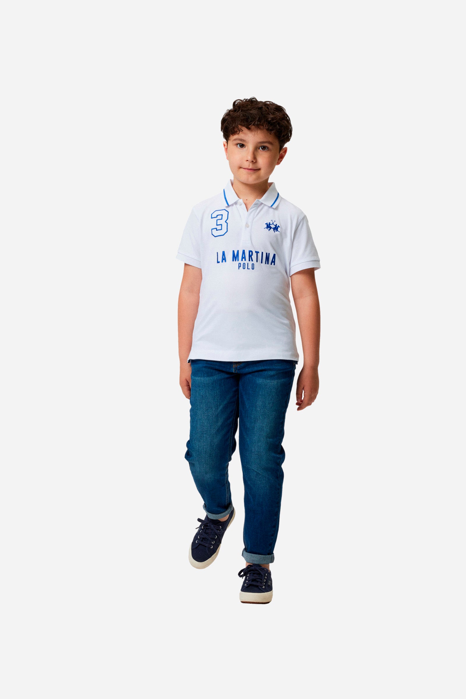 Boys' single-colour polo shirt made of pique cotton. Profiled collar, with contrasting colour thread. Fastens with two buttons. Also featuring embroidered lettering in contrasting colours on the front. The logo is embroidered on the chest, left side. - Optic White/Blue