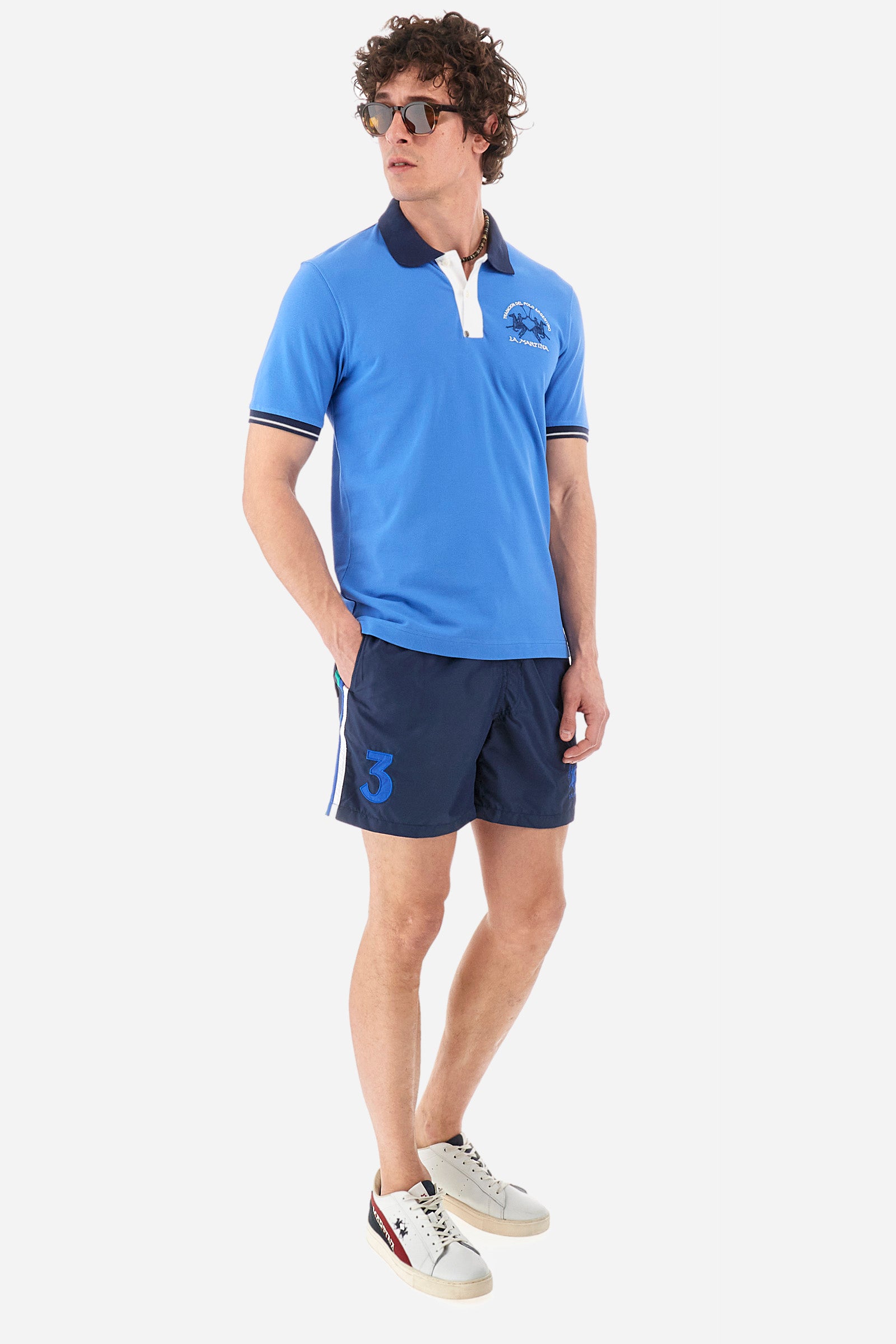 Men's single-colour short-sleeved polo in elasticated cotton. Fastens with two contrasting buttons. Ribbed collar and armholes in different shades. The "La Martina" lettering can be found under the collar. A large logo is embroidered on the chest. The fit is slim. The model wears a size L. - Campanula