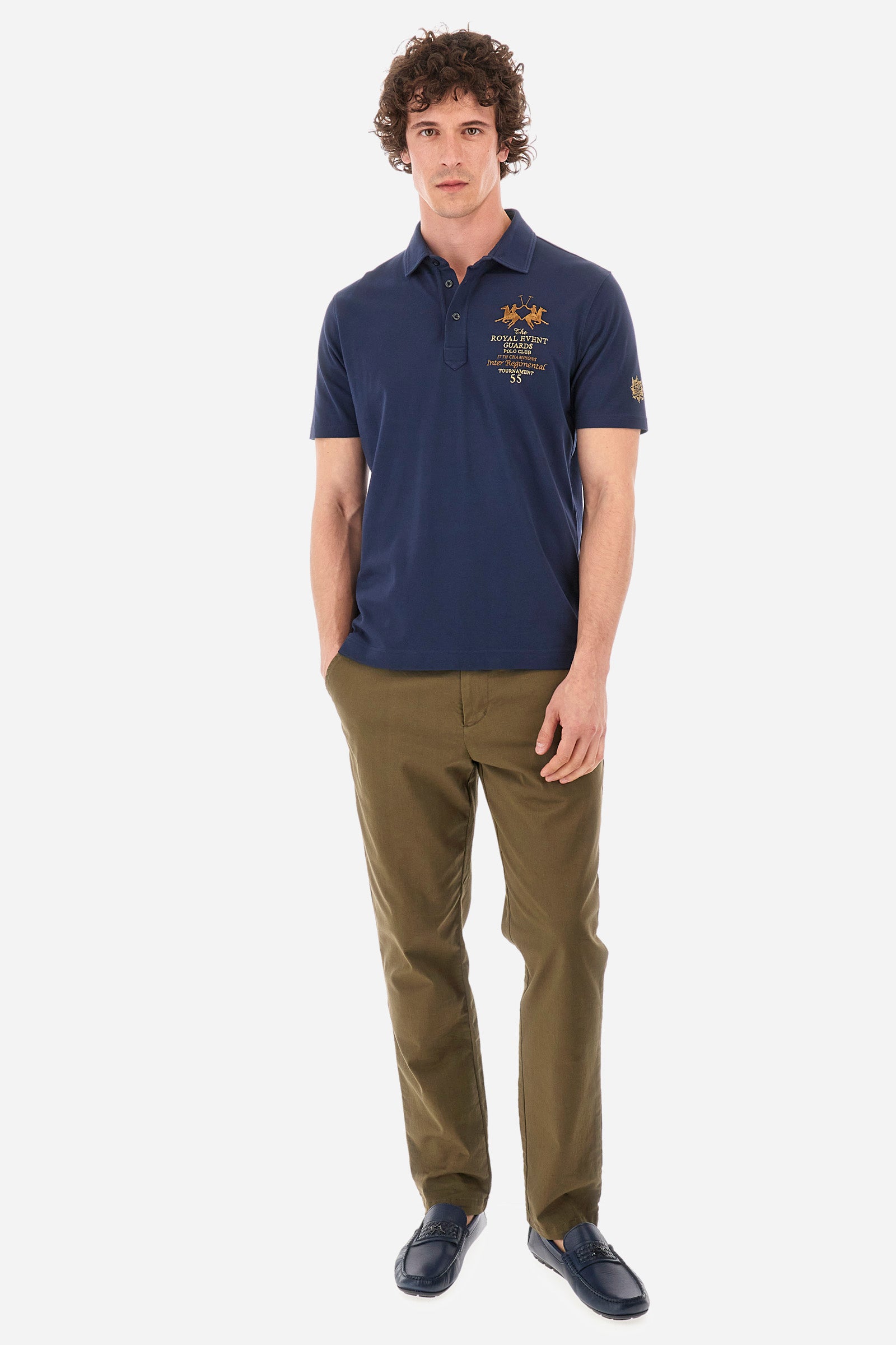 Men's short-sleeved single-colour polo shirt in elasticated cotton. Two-button fastening. Pointed collar. On the front we find copper-coloured lettering and a large logo. On one of the sleeves there is a symbol representing the Guards line. The fit is regular. The model wears a size L. - Navy