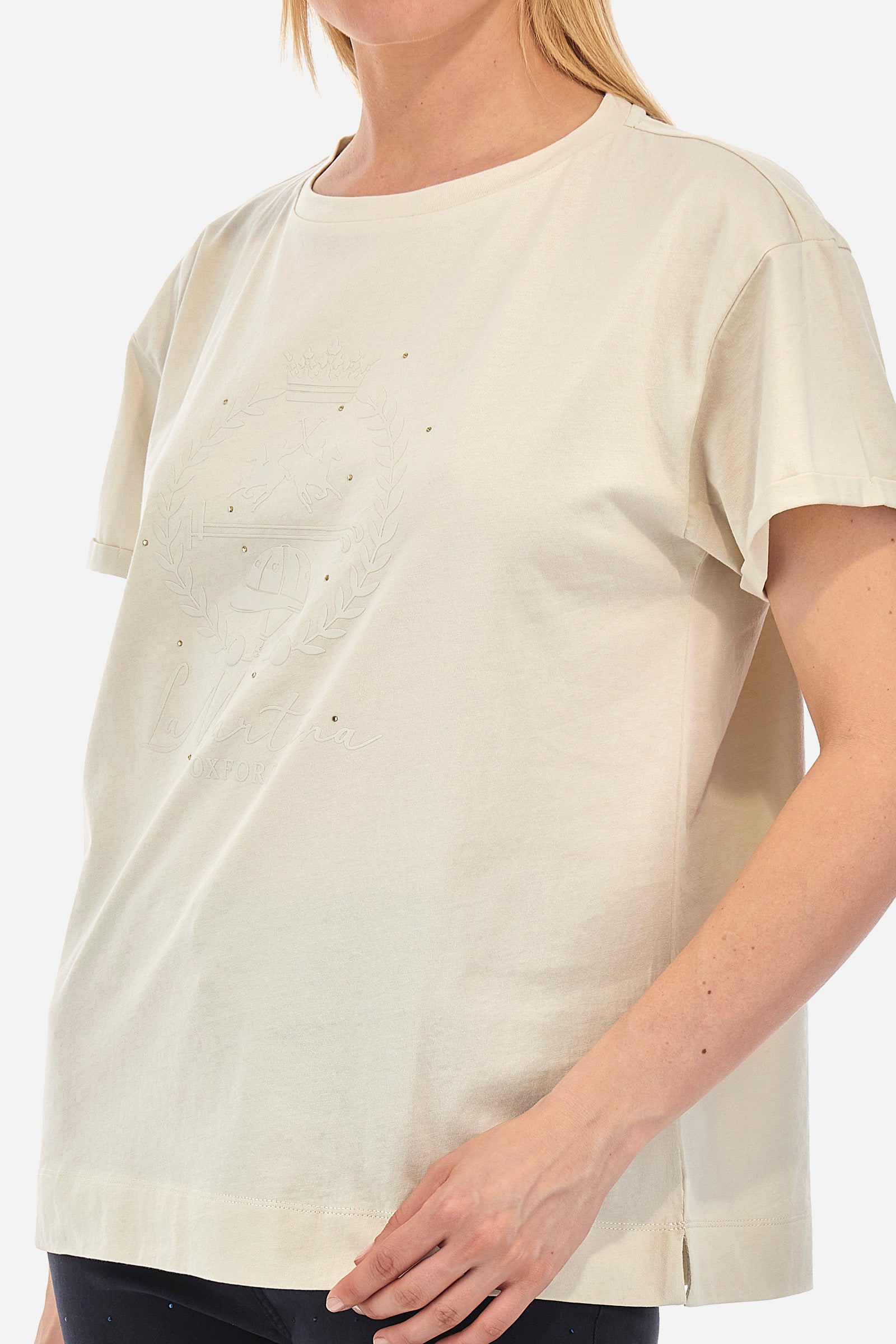 Women's short-sleeved T-shirt with a crew neck in a single colour from the Polo Academy line. Made of 100% cotton. There is a slight turn-up on the sleeve. The front features the La Martina logo and lettering and some of the symbols of the Polo Academy line, all tone on tone. The T-shirt is embellished with all-over tone-on-tone rhinestone applications. The fit is regular. The model wears a size 2. - Bone White